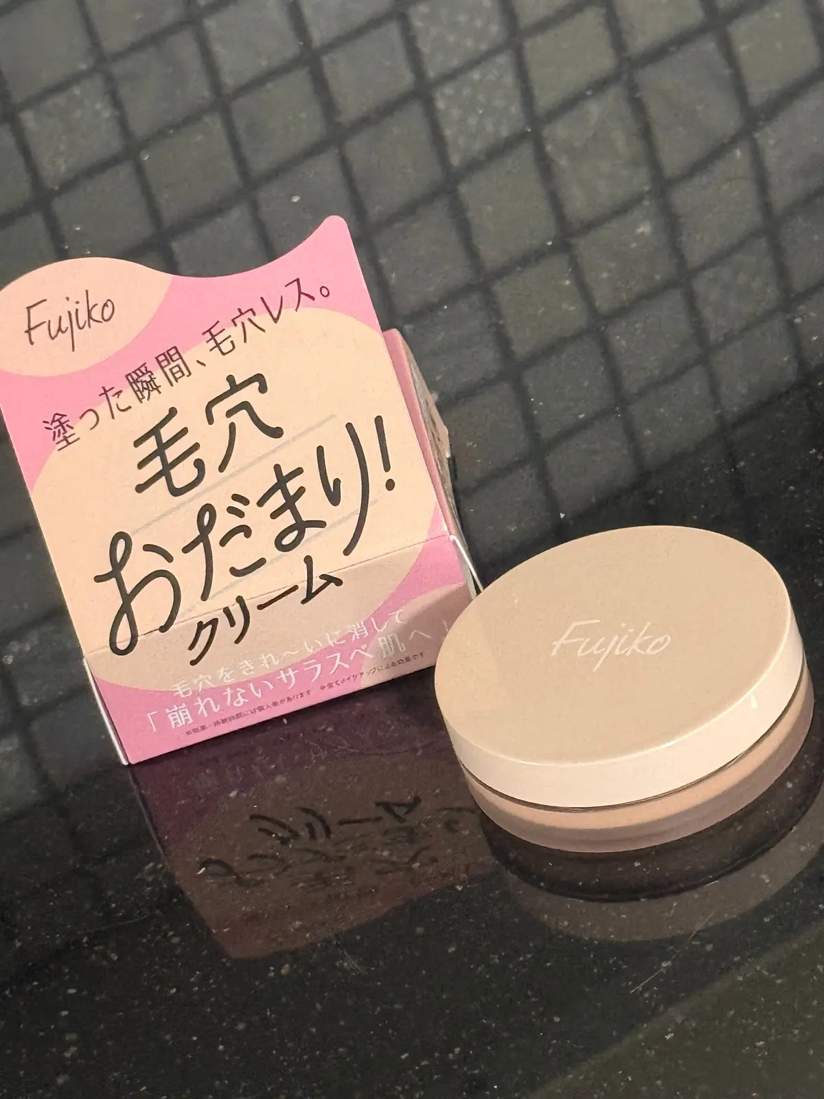 Fujikoのピンクとベージュの箱と、ベージュの円形容器がアスファルトの上に置かれている