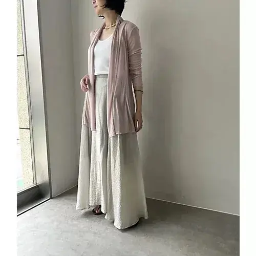 女性が白い傘を差して歩き、茶色の服を着て白いトートバッグを肩にかけた姿