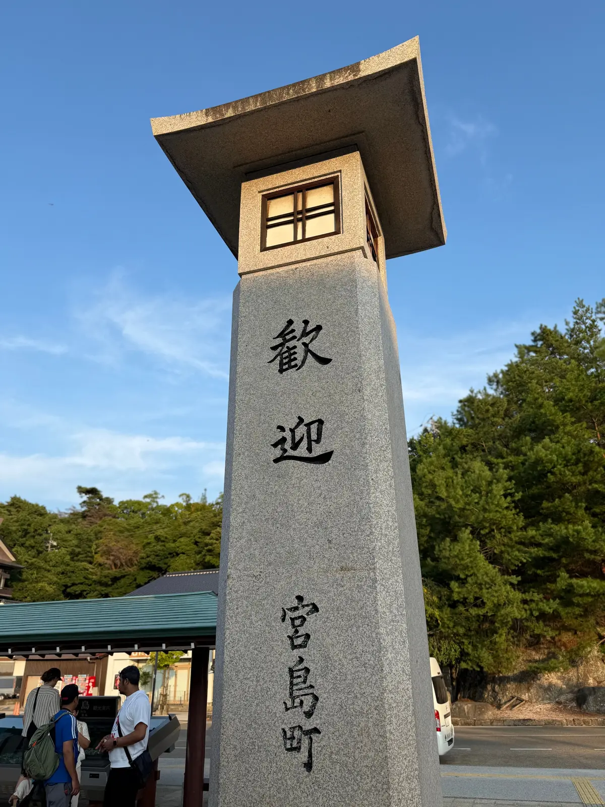 灰色の石柱に黒い文字で「総社郷」と書かれた案内板。上部には屋根があり、背景に緑の丘と青空が広がる。