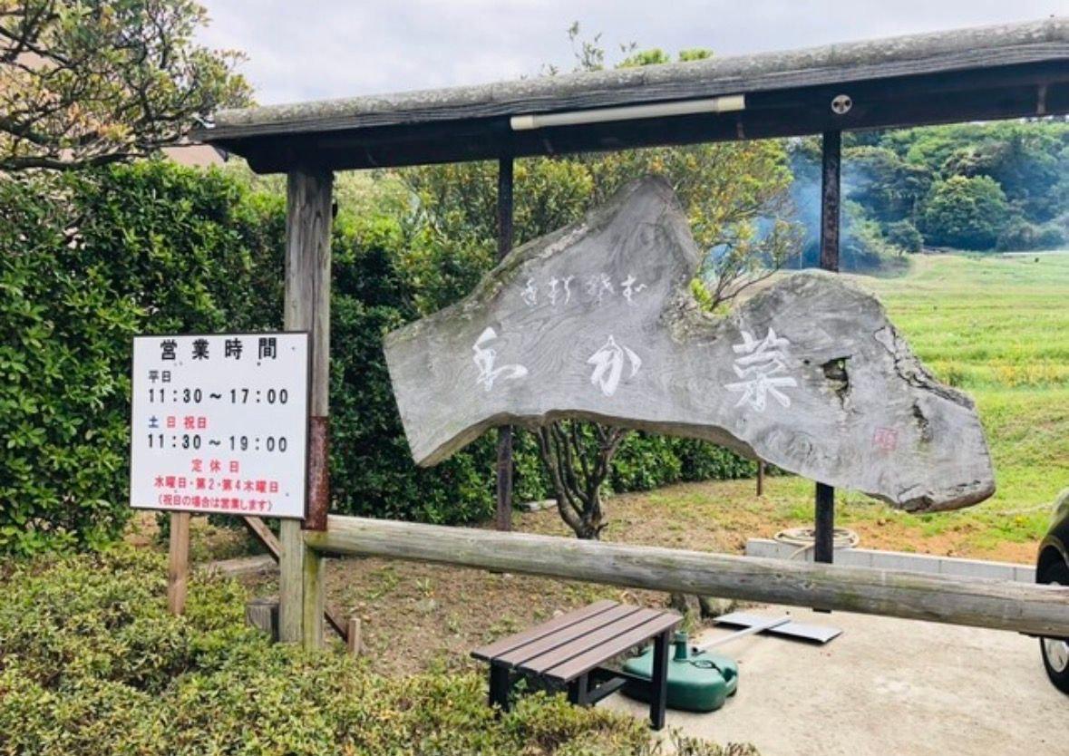 木製の屋根付き休憩所で、石の看板に「吉田家跡地」と刻まれ、左側に営業時間表がある