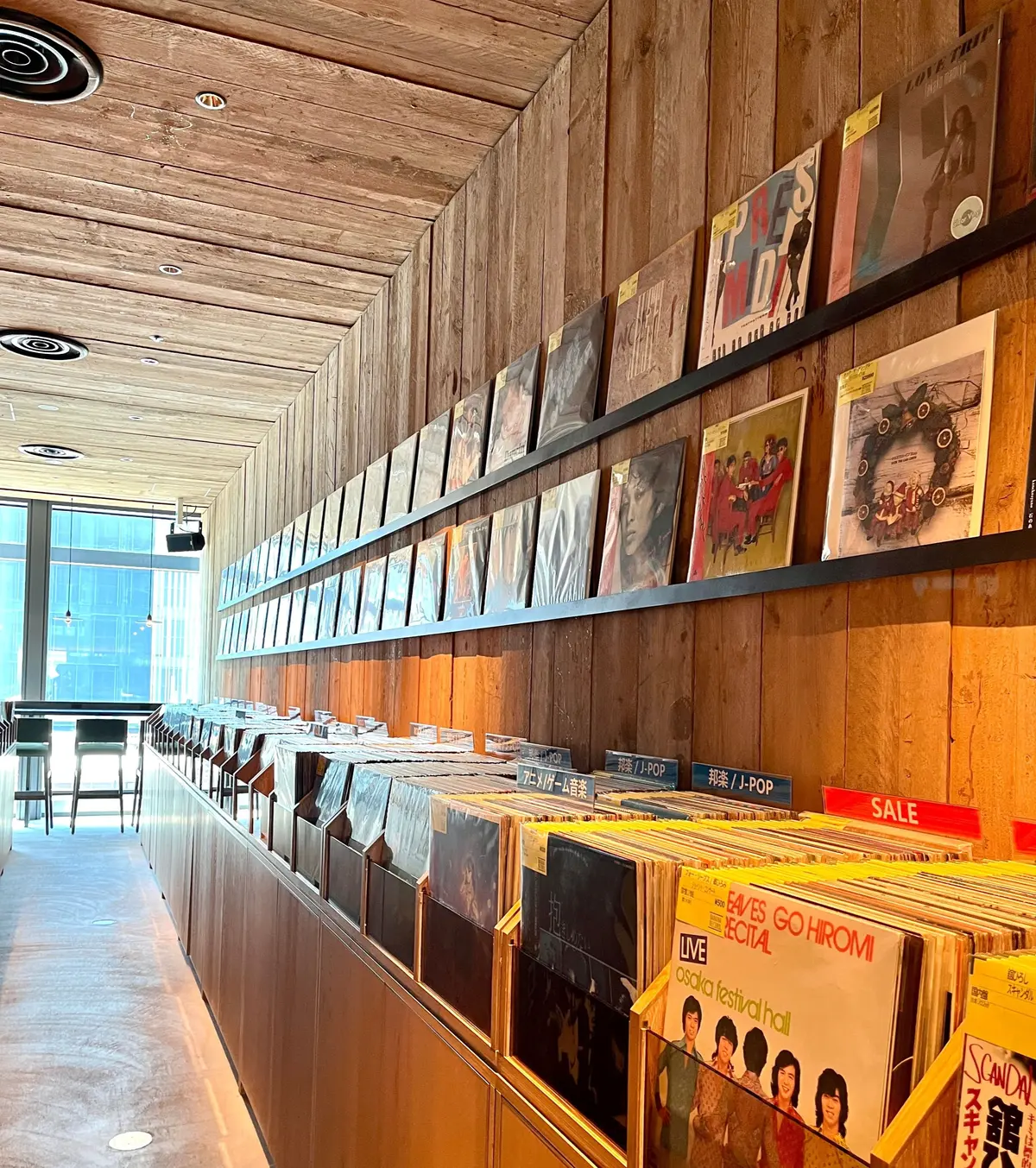 木製棚に多数の中古レコード。壁にはアルバムジャケットの展示
