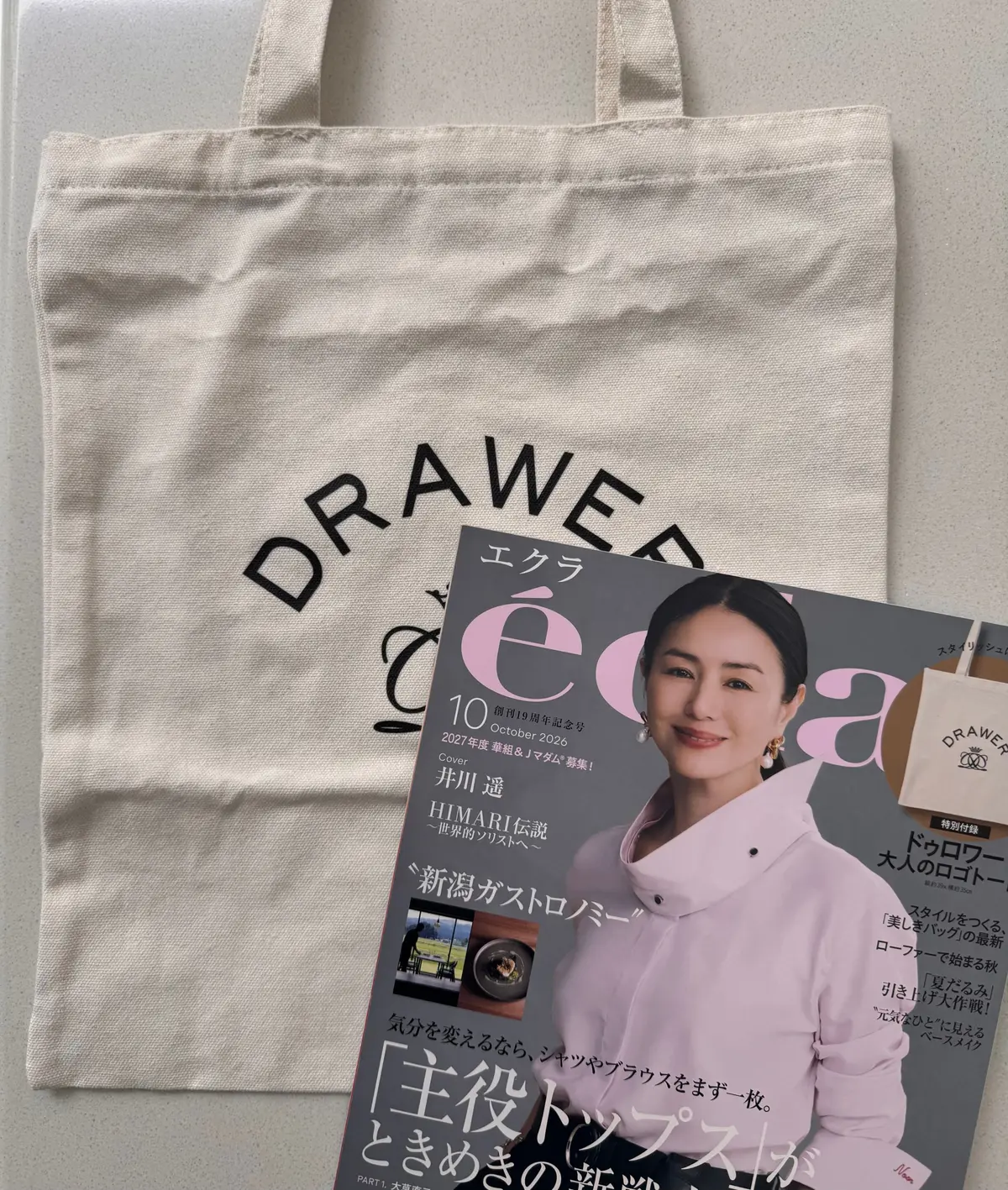 雑誌「DRAWER」10月号の表紙。モデルの非鳥遥が笑顔で座っている。背景はベージュ色の壁で、雑誌のタイトルロゴが上部に大きく配置されている。