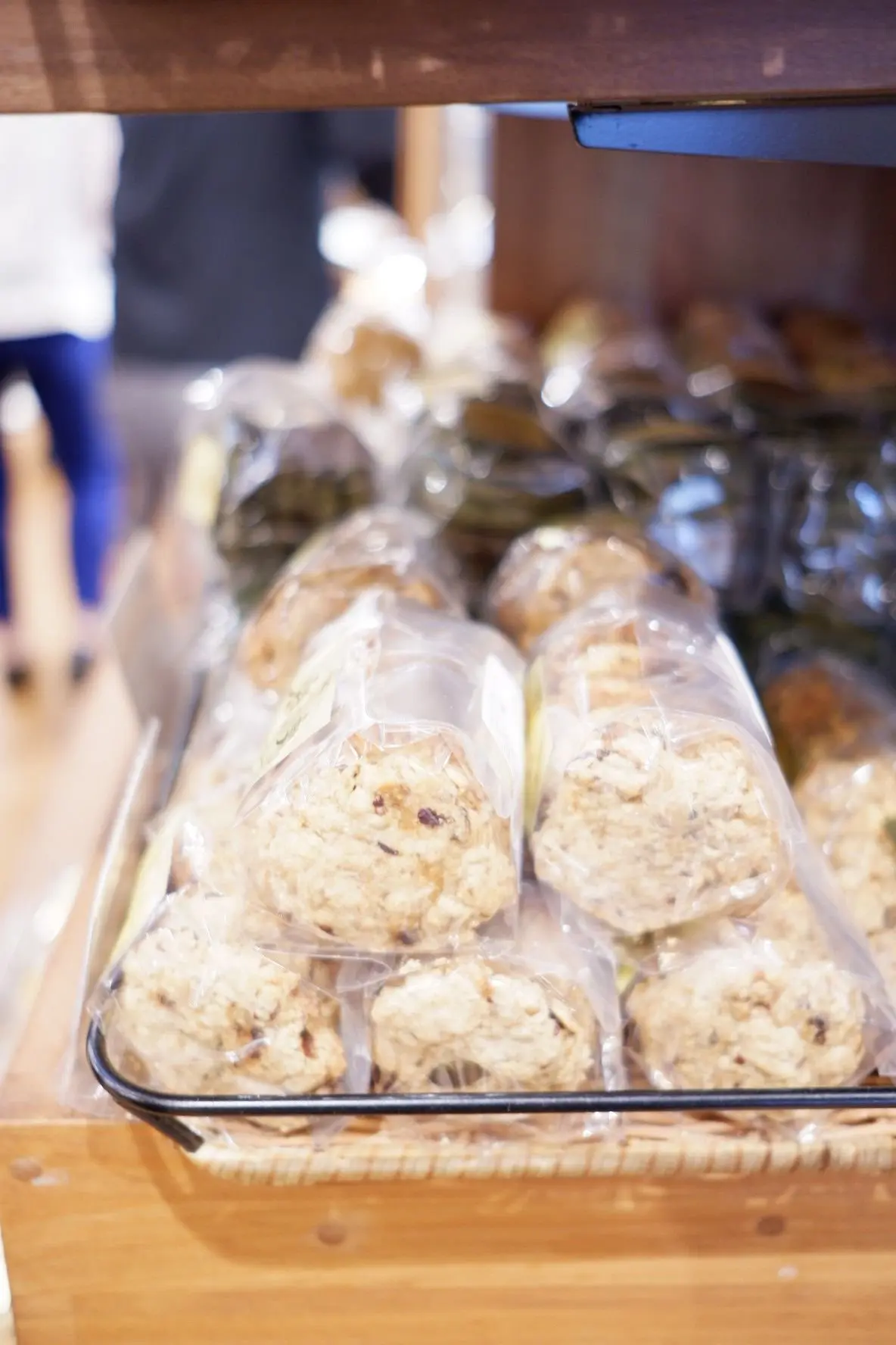 木製の棚に並んだ、透明な袋に入ったクッキー。手前にはオートミールクッキーが複数、奥には緑色のものが並んでいる。