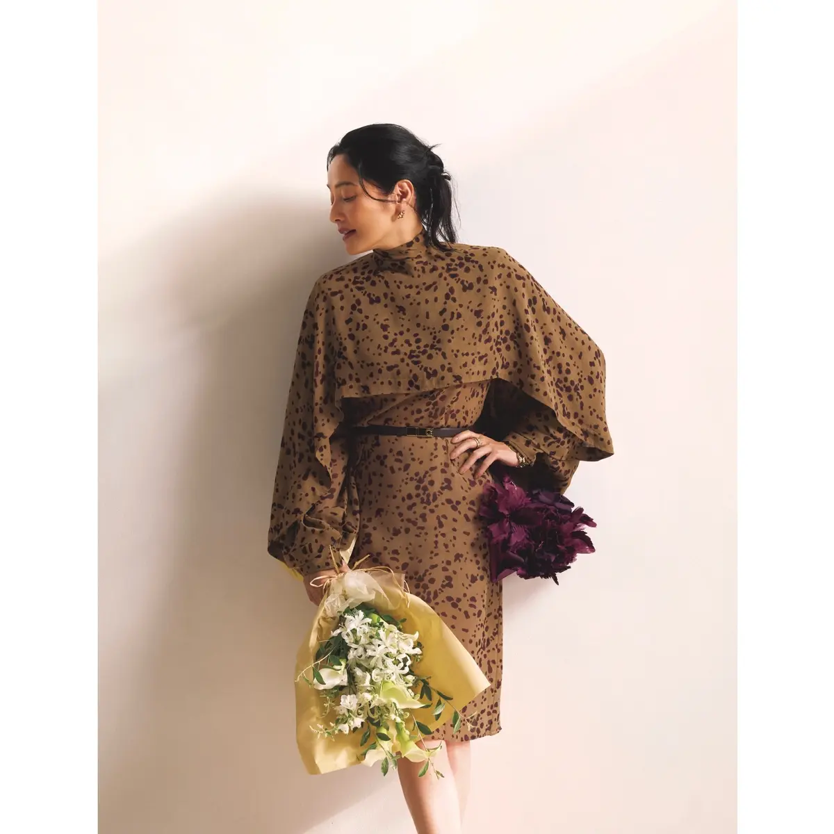 キャメル地にプラム色のオーキッドプリントを配した膝丈のドレスに、ウエストに黒の細ベルトを付けたコーディネート　モデル・熊沢千絵