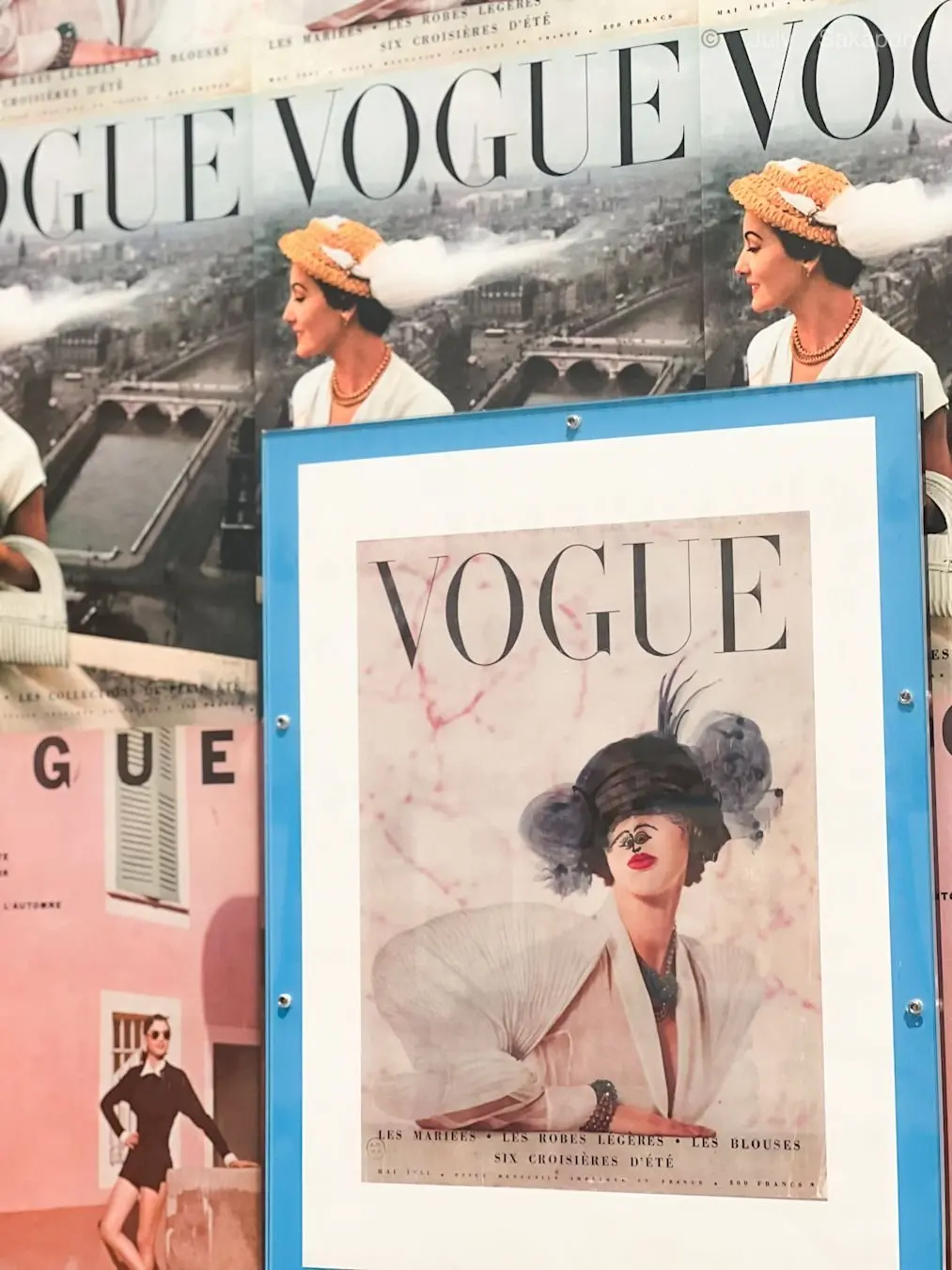 VOGUEのポスターが複数並び、中央に女性がエレガントな帽子と服装で描かれている