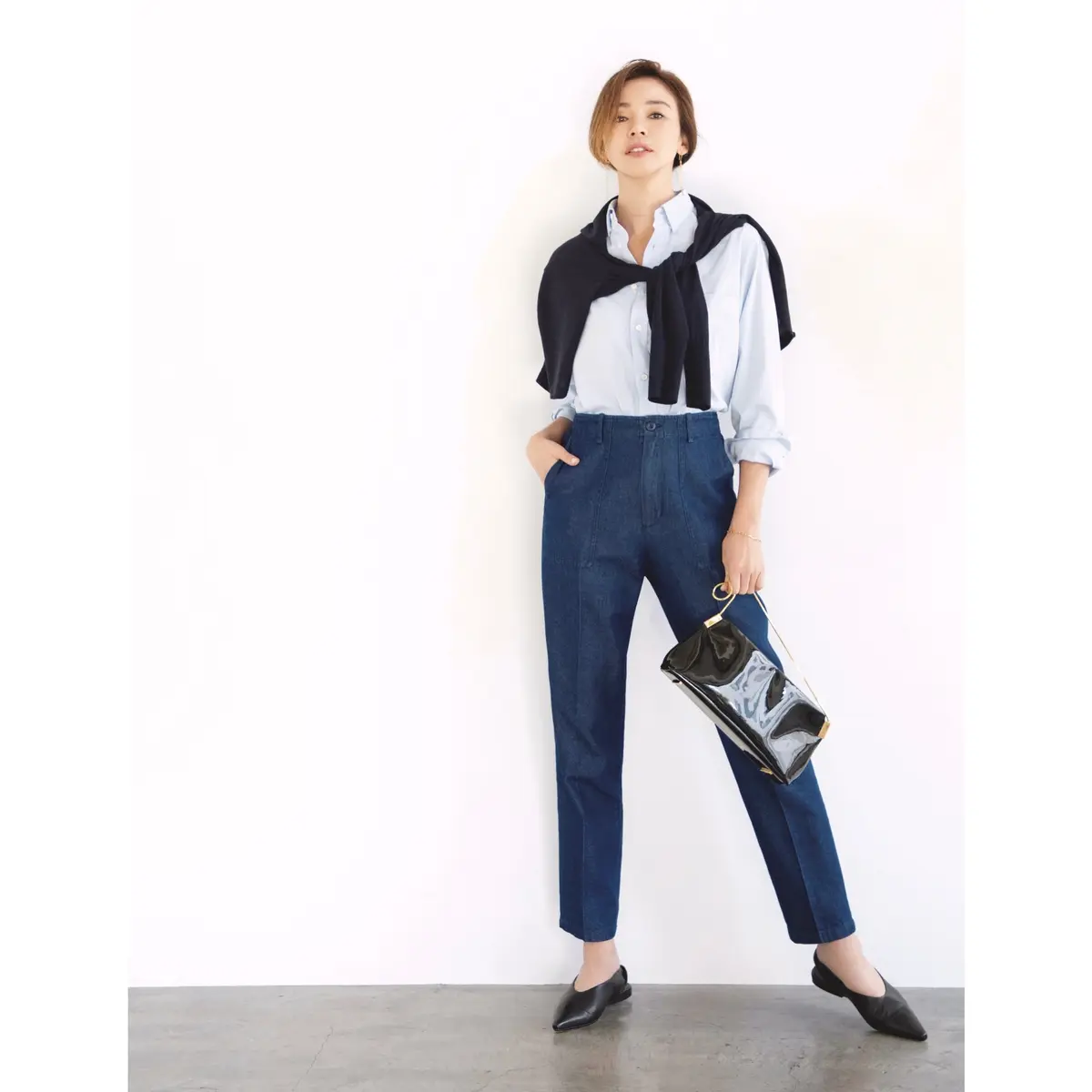 ブルーデニムパンツにライトブルーシャツを合わせ、黒ニットを肩がけしたコーディネート　モデル・SHIHO