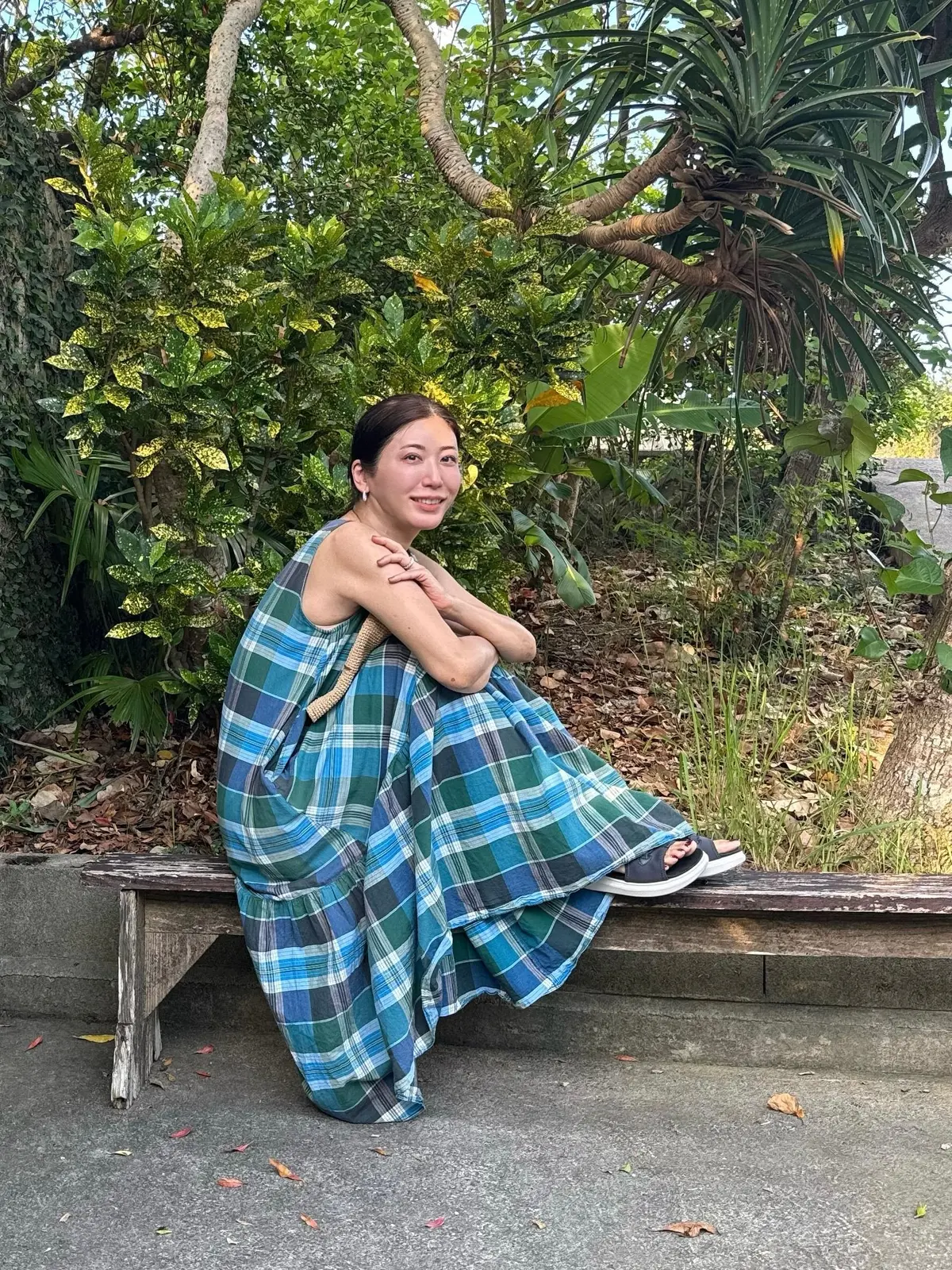 無印良品のチェックワンピースに、麦わら帽子を持っている女性