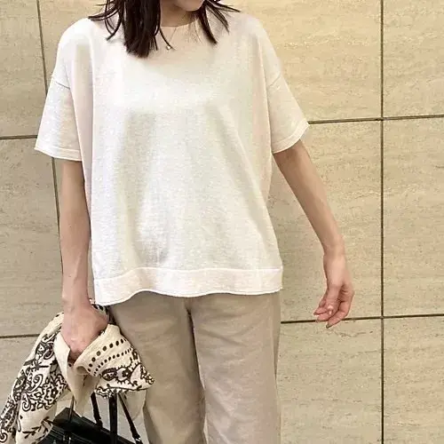 女性が白い傘を差して歩き、茶色の服を着て白いトートバッグを肩にかけた姿