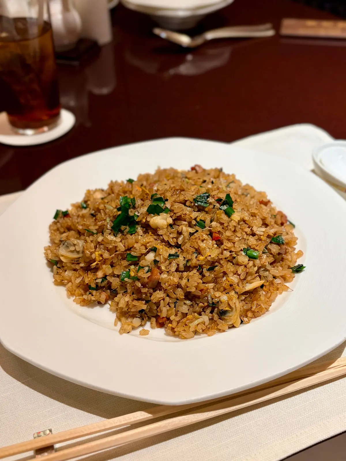 白い長方形の皿に、緑の野菜やキノコを散りばめたチャーハンが盛り付けてある
