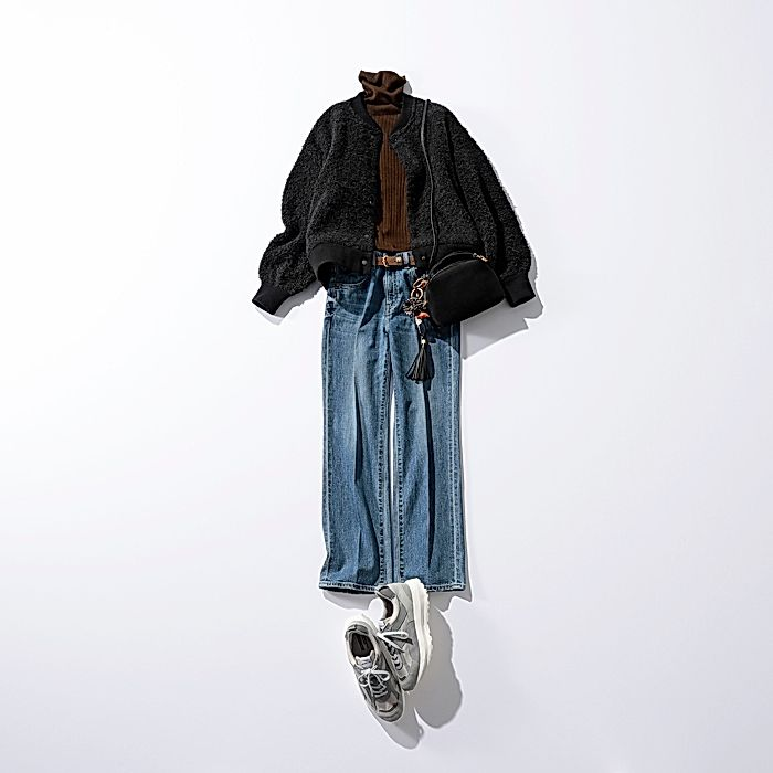 白い背景に、黒いボア素材のジャケット、茶色のタートルネック、デニムのワイドレッグパンツ、白いスニーカーが平らに配置されたファッションコーディネート写真。黒いバッグがパンツにぶら下がっている。