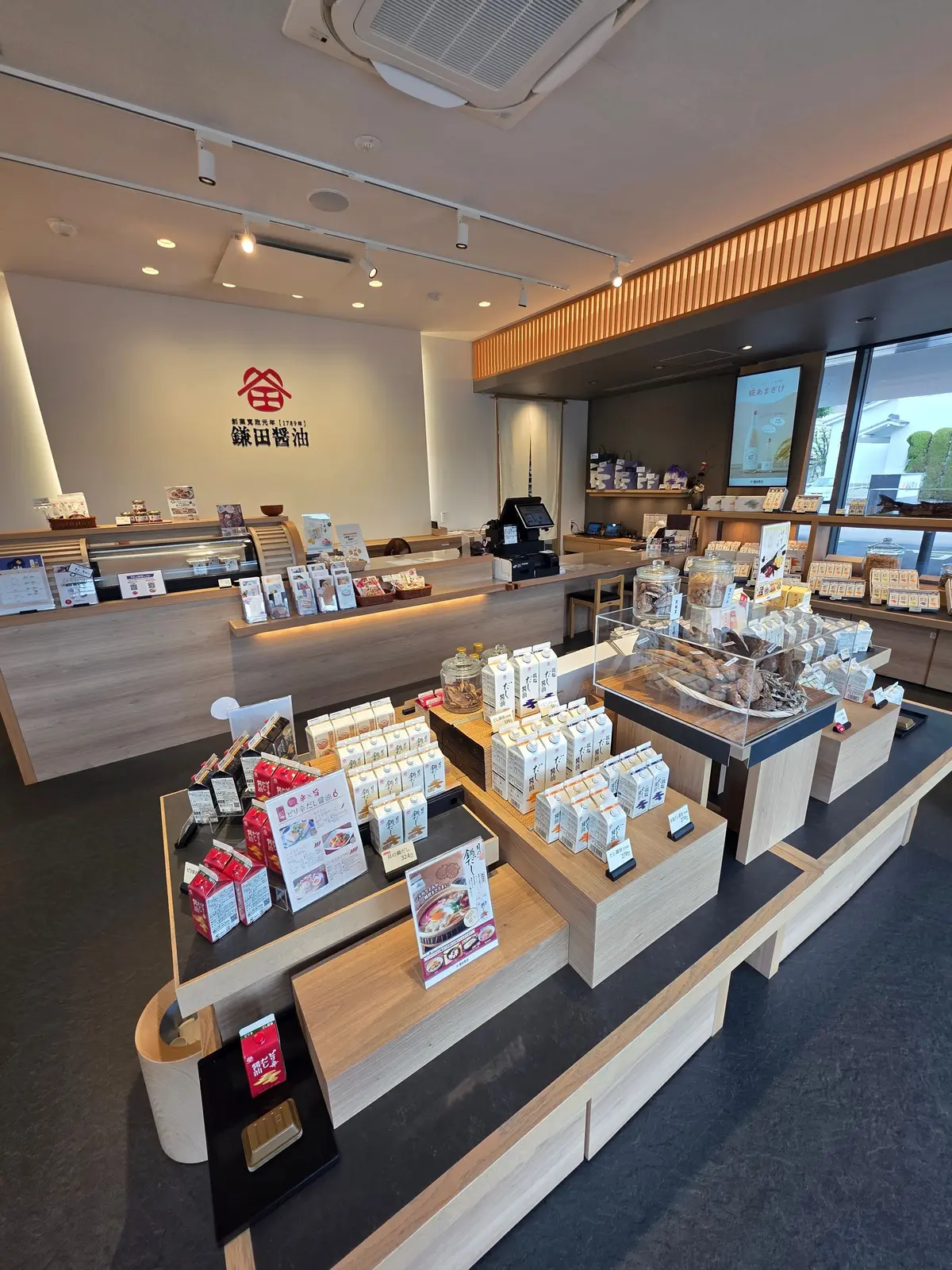 木製のカウンターに商品が並ぶ店舗の様子。奥には窓があり、外の緑が見える。壁には「藤田養池」のロゴマークがある。