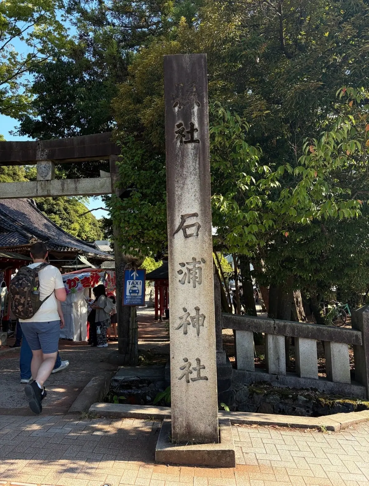 石碑に「石淵神社」の社名が墨で書かれた、日本の神社入口の様子。背景には鳥居と緑豊かな木々が見える。