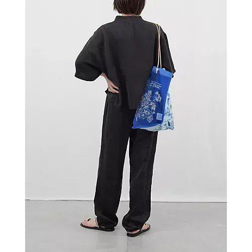 黒色のシャツとパンツを着用した人物が背中を向けて立っている。右手に青色の巾着バッグを持ち、ベージュ色の紐で肩にかけられている。背景は白。