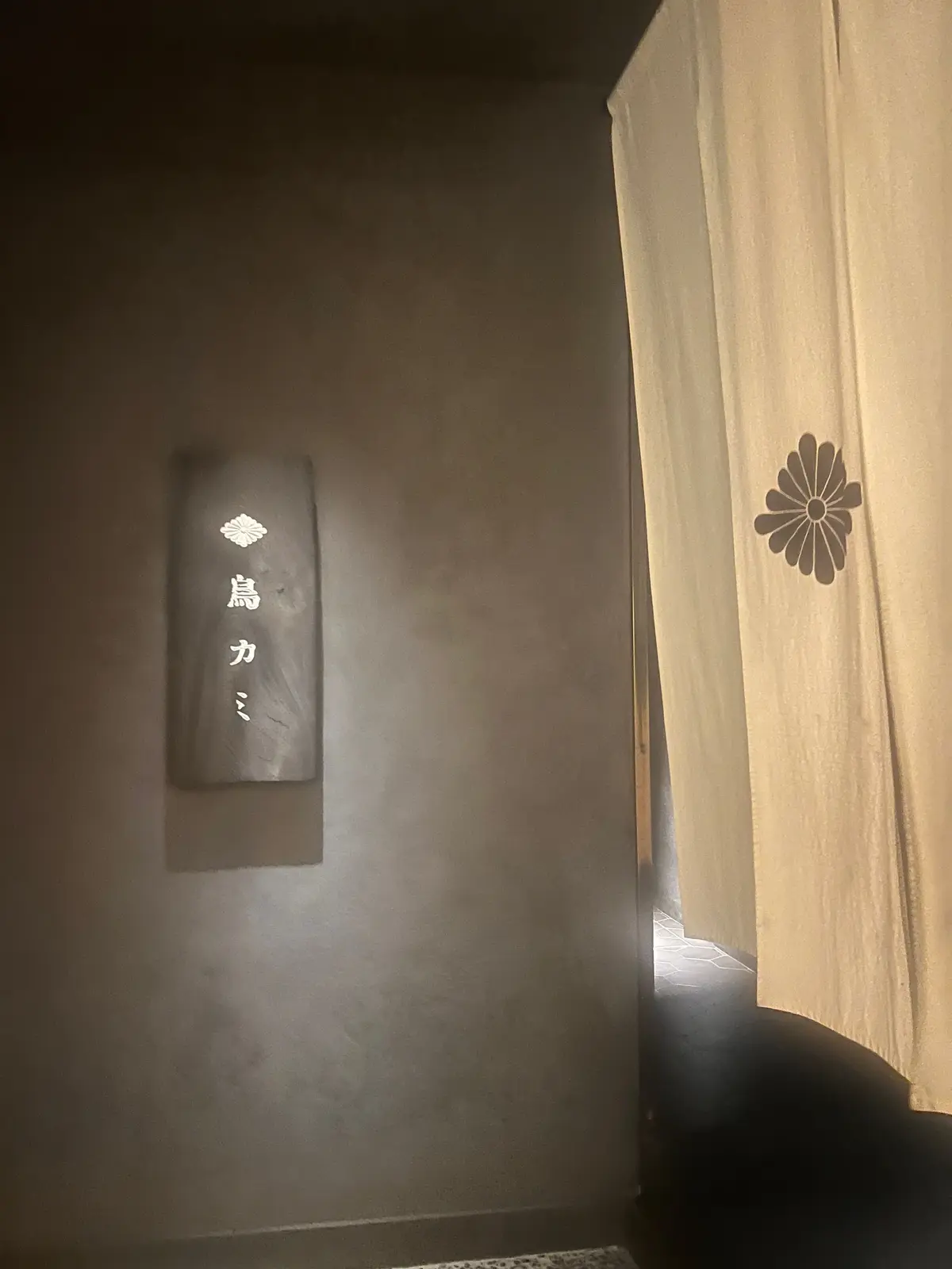 浴室の壁に「湯カビ」と書かれた長方形の看板があり、左側に花の模様が描かれている。右側には花の模様が付いたカーテンが垂れ下がっている。