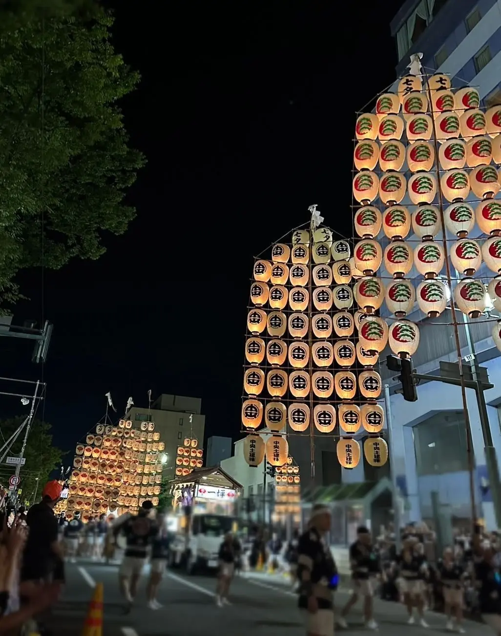 夜の街並みに、ちょうちんや提灯が飾られた祭り風景。赤と白の提灯が密集し、中央には「七五三」の文字が見える。道路には多くの人が集まっている。