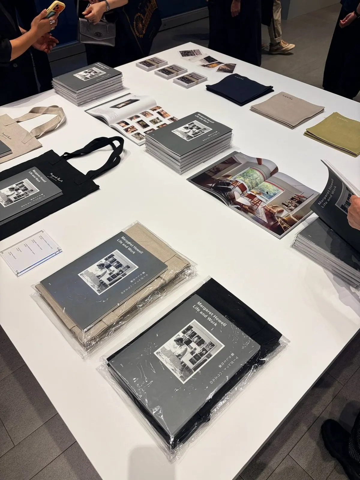 白いテーブルに、マーガレット・ハウェル写真家の書籍やトートバッグが並んでいる。黒と白のモノクロ写真が多く、一部にカラー写真の書籍もある。