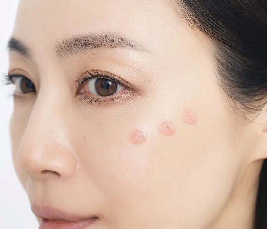 目じりの下から入れて 上＆外寄りに広げる　女性の下半身の顔がアップで、鼻周りに複数の淡いピンク色のニキビが散在している