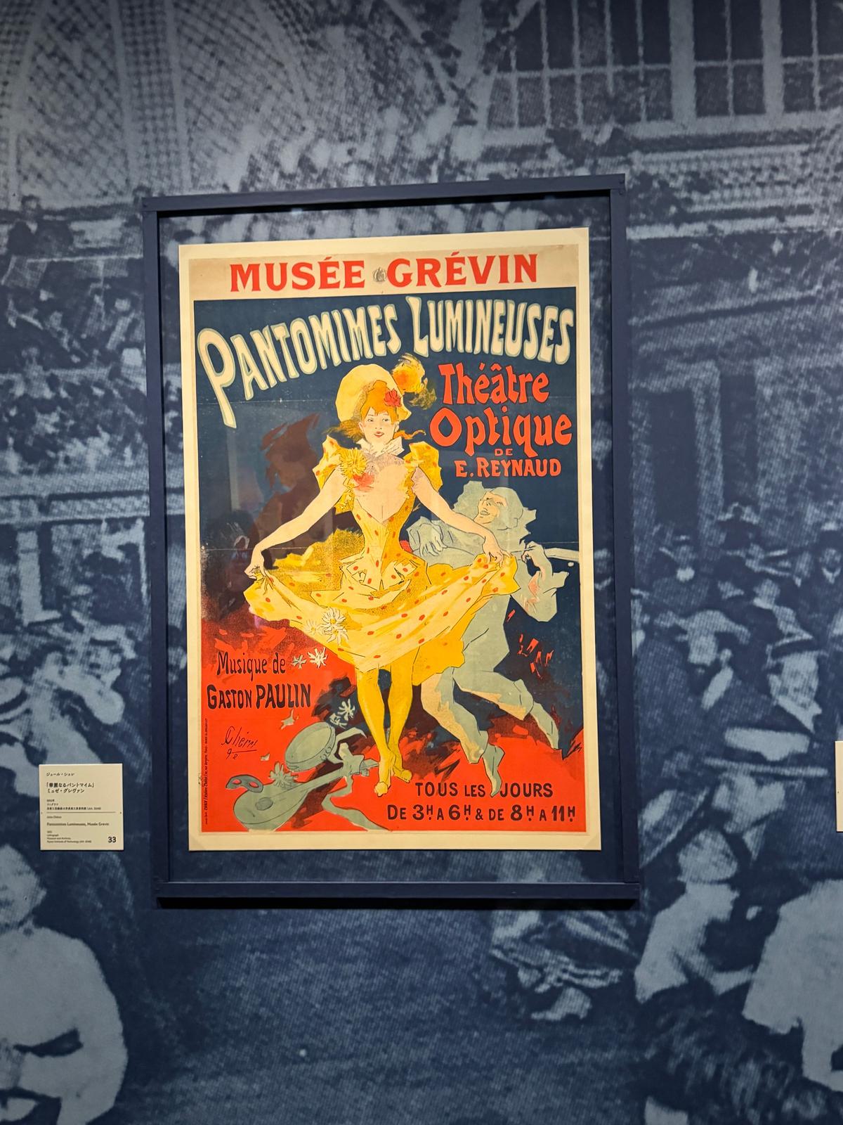 グレヴィン美術館の額装されたポスター。タイトルは「Pantomimes Lumineuses」。黄色と赤を基調としたデザインで、女性と男性の踊り手のイラストが描かれている。下部にはテキストと日付が記載。背景にはモノクロの人物写真が配置。