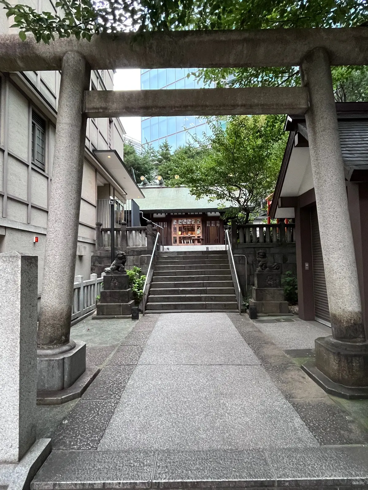 石造りの建物の入り口脇に、緑の植栽に囲まれた「ブルーボトルコーヒー バーニーズ ニューヨーク」の案内板が立っている様子。石畳の小道が建物内に続いており、ガラス張りの店内が見える。
