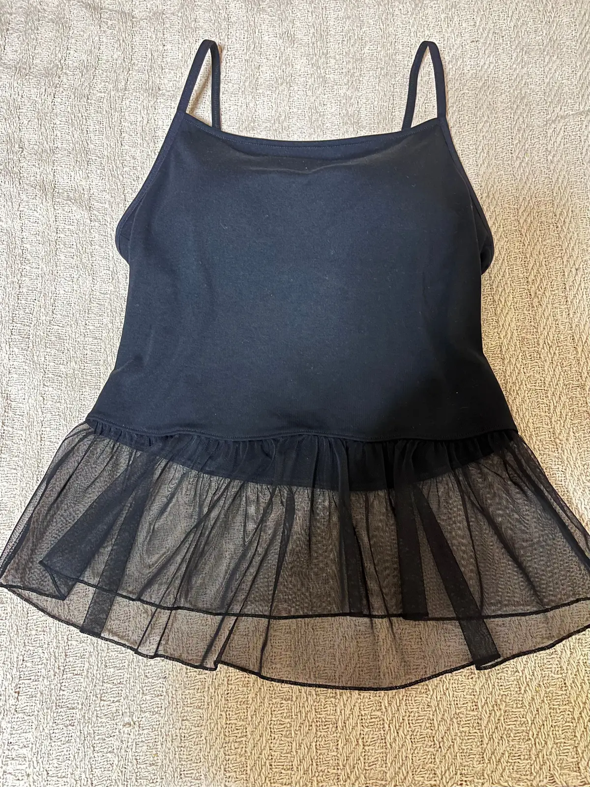 黒いタンクトップに、裾に黒いチュールスカートが縫い付けられたトップス。肩紐があり、全体的にシンプルなデザイン。