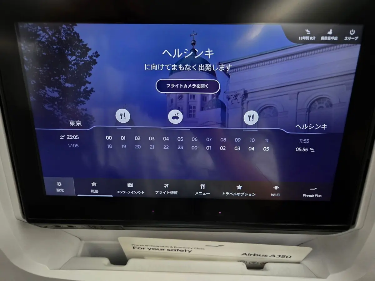 航空機の座席に設置されたエンターテイメントシステム画面。ヘルシンキの観光名所マップが表示されており、時間帯ごとの混雑状況が示されている。画面下部には、設定、機内モード、エンターテイメント、フライト情報などのアイコンが並んでいる。