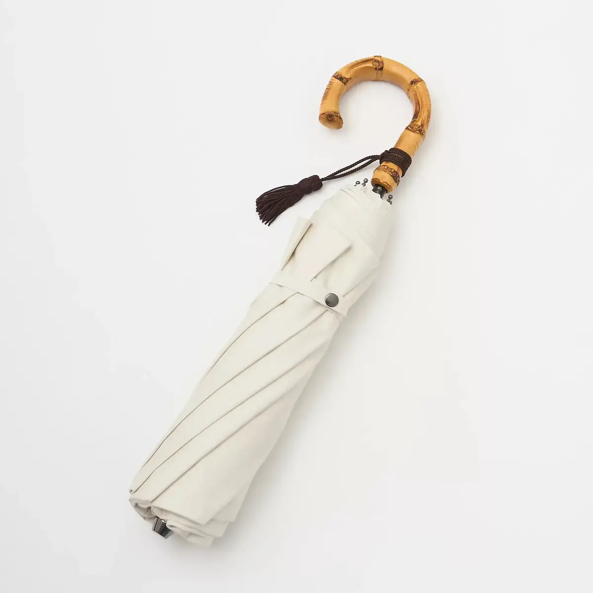 白い傘が竹製の柄で、黒いタッセルが付いたデザインです。