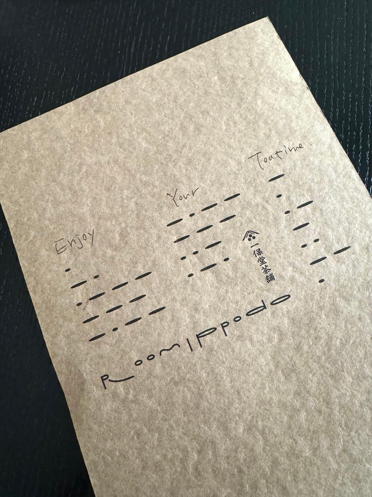 茶色の紙に「Enjoy Your Tea Time」と手書きの文字と点線が並ぶ
