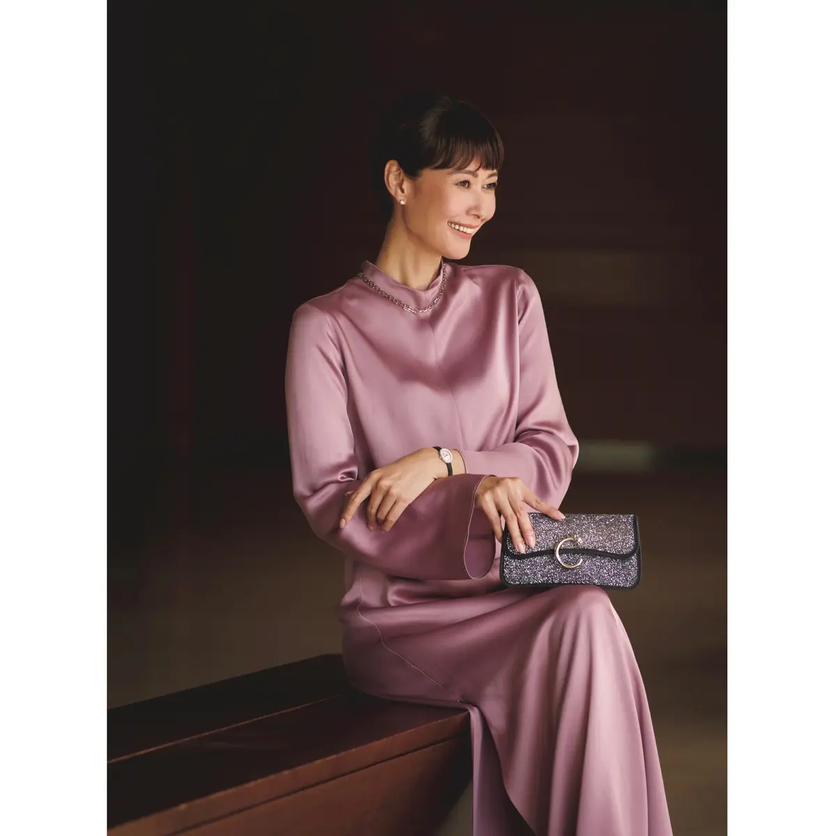 ピンクサテンのドレスにパープルグリッターのクラッチバッグを持ったコーディネート　モデル・田丸麻紀