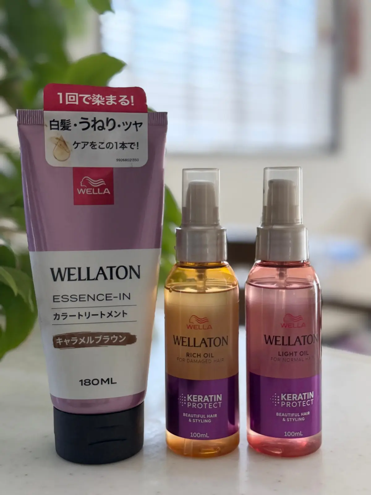 ウェラ（WELLATON）のヘアケア製品3点。左から、180mlの黒いチューブ容器に入った「エッセンスイン」ケアオイル、右から100mlのオレンジ色のボトルに入った「リッチオイル」、100mlのピンク色のボトルに入った「ライトオイル」。