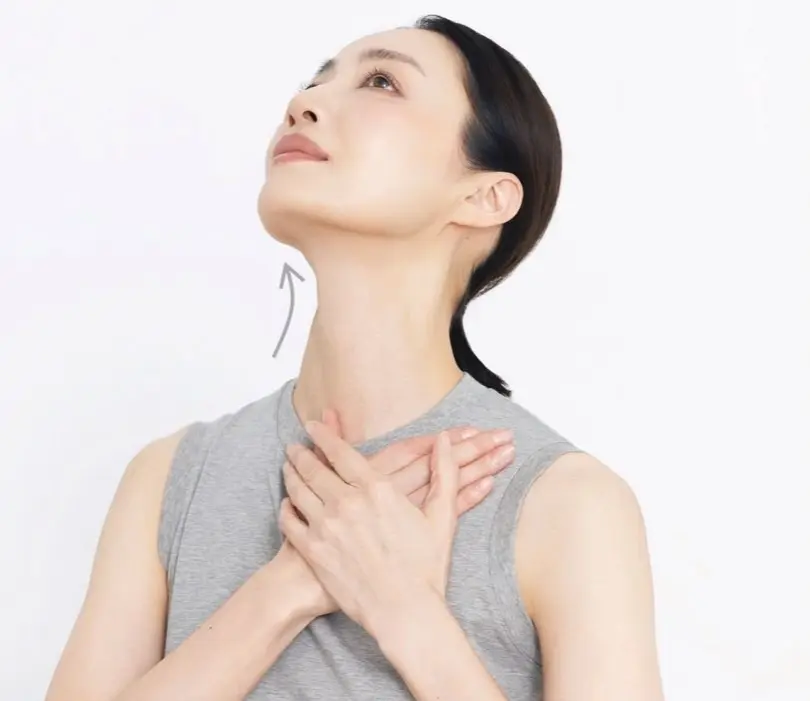 女性が首を上に向け、胸に手を当てています。首に曲がった矢印が描かれています。
