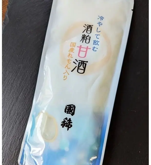 白い個包装の酒粕甘酒のパック。パックには商品名「酒粕甘酒」と、その他の文字が記載されている。