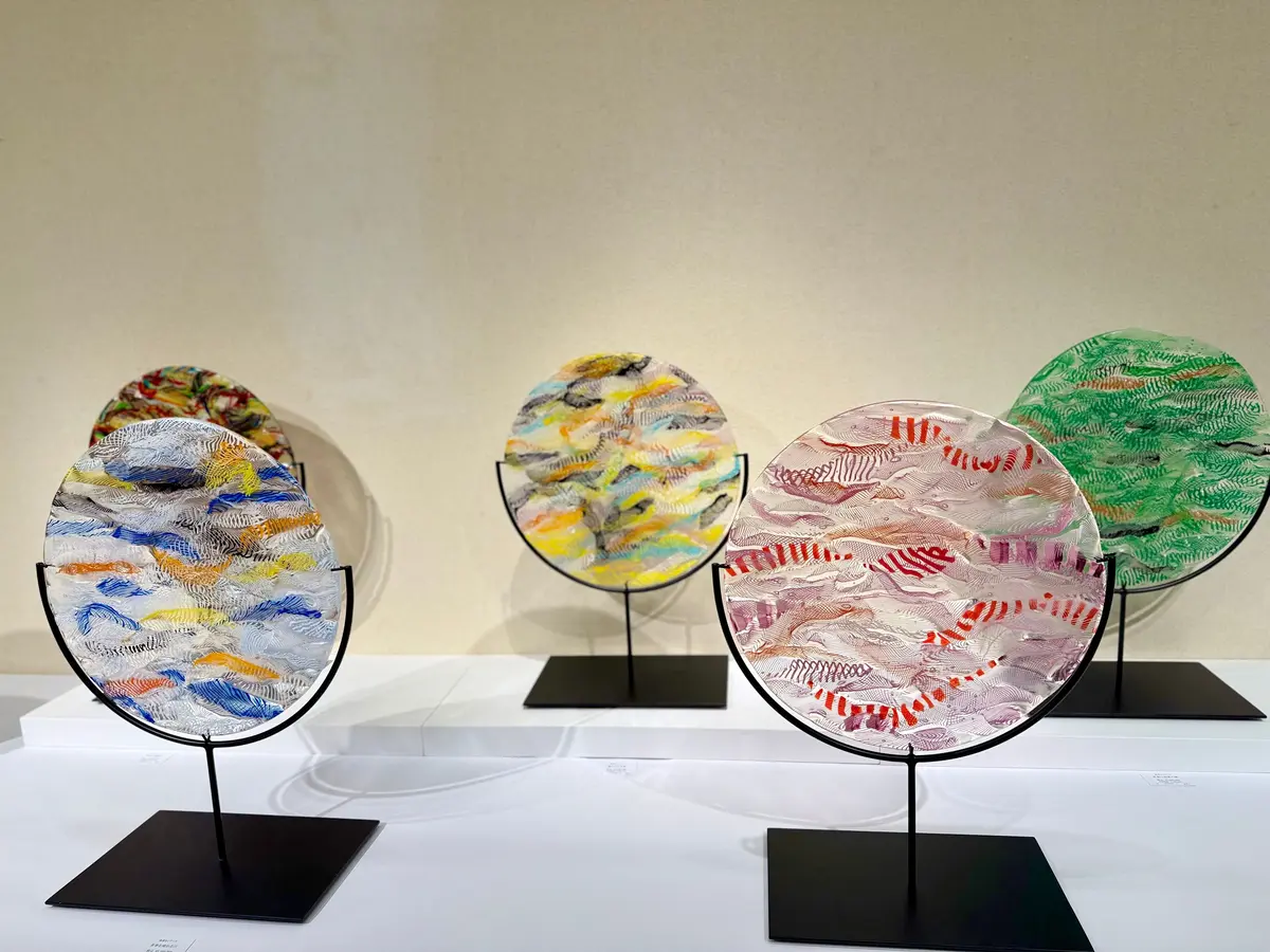 黒い台座に立つ、半円形のガラス作品が4つ並んでいる。それぞれ異なる色彩で、抽象的な風景画が描かれている。左から青と白、茶色と黄色、ピンクと赤、緑と黒のグラデーション。