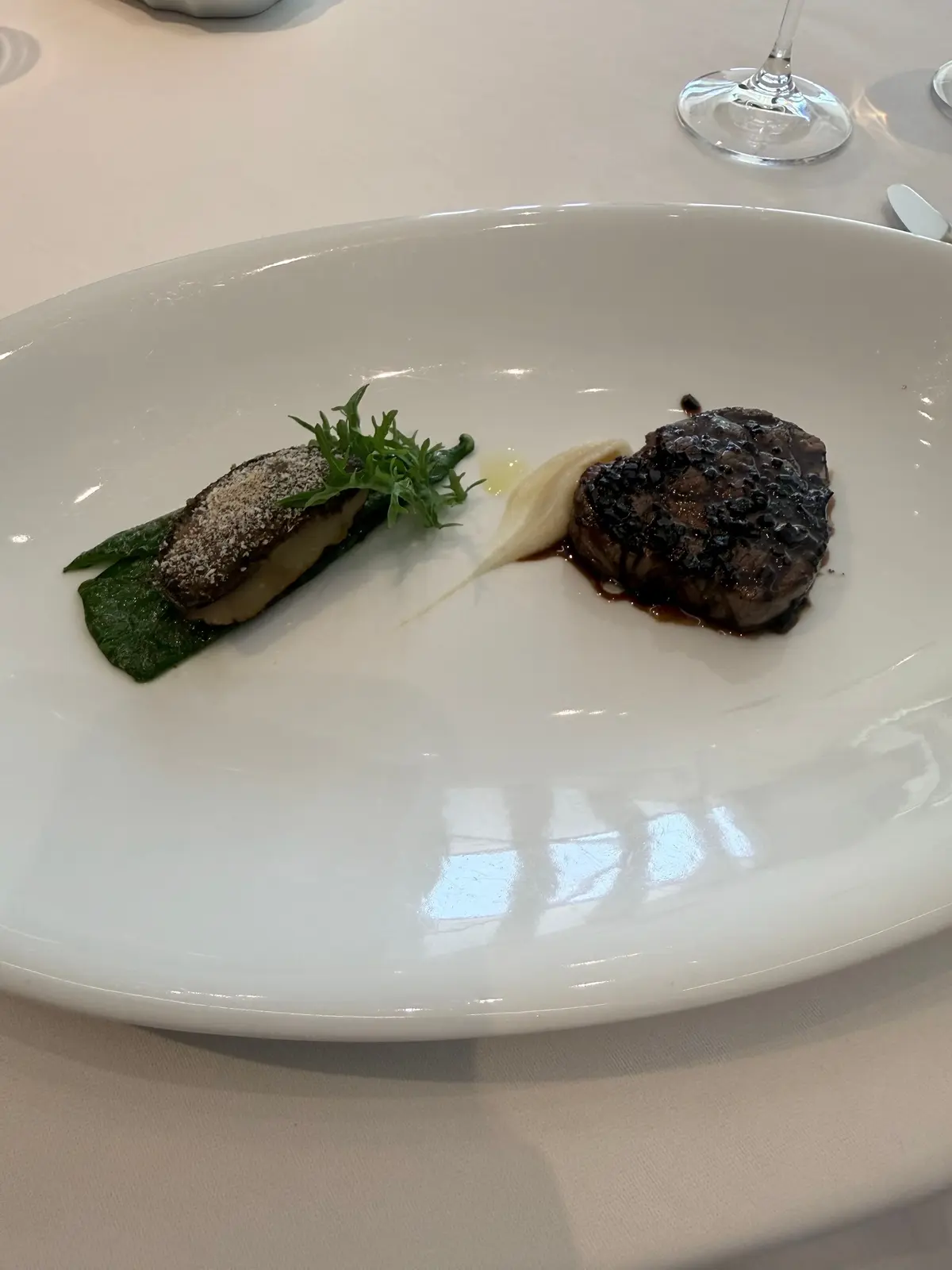 白い皿に、肉と野菜の盛り合わせ。左にはソテーされたマッシュルーム、右には肉のロースト。それぞれにソースとハーブが添えられている。
