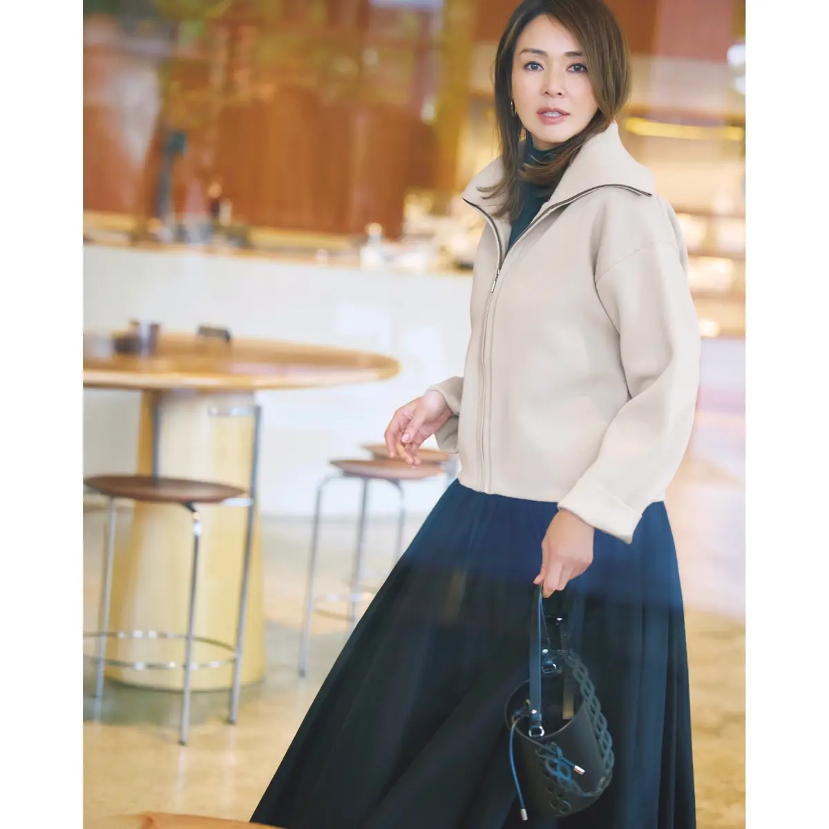 ライトベージュのブルゾンに黒タートルネックトップスと黒ギャザースカートを合わせたコーディネート　モデル・SHIHO
