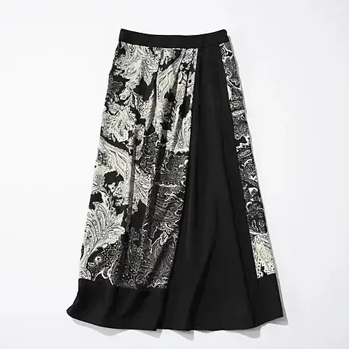 黒と白のペイズリー柄と黒色のパネルで構成されたミモレ丈スカート。右側に黒色のパネルがあり、左側は柄が入り、裾にかけて広がるAラインシルエット。
