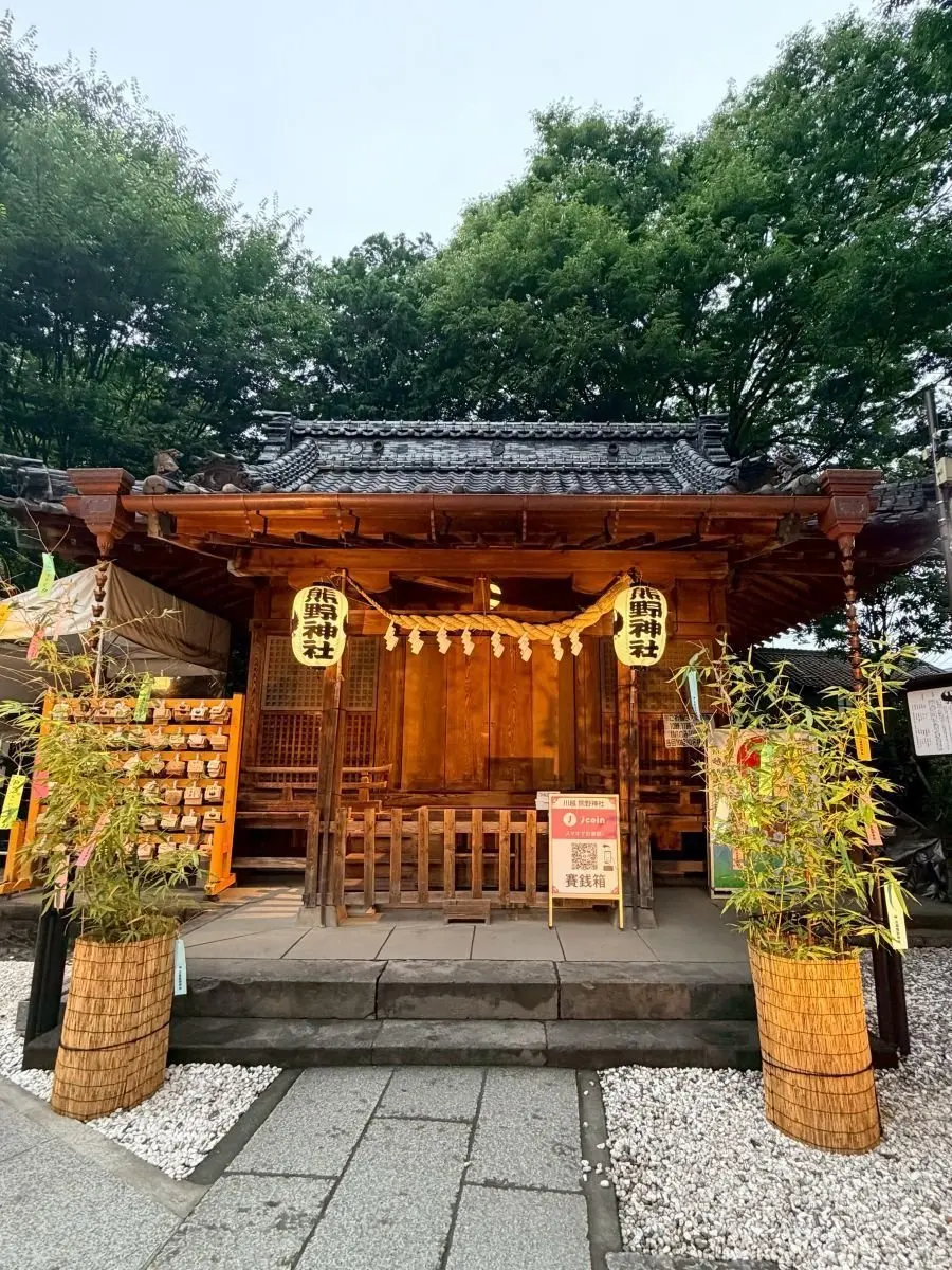 木造の神社社殿、木製の鳥居と手水舎、両側に竹の鉢、緑豊かな木々が背景にある