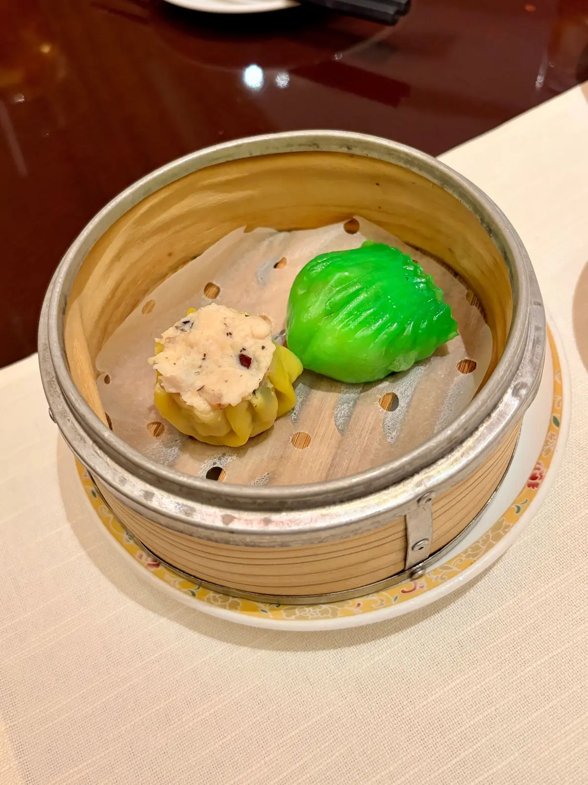 蒸し器内の点心と緑色のデザート、黄色の皮とクリームをかけたもの