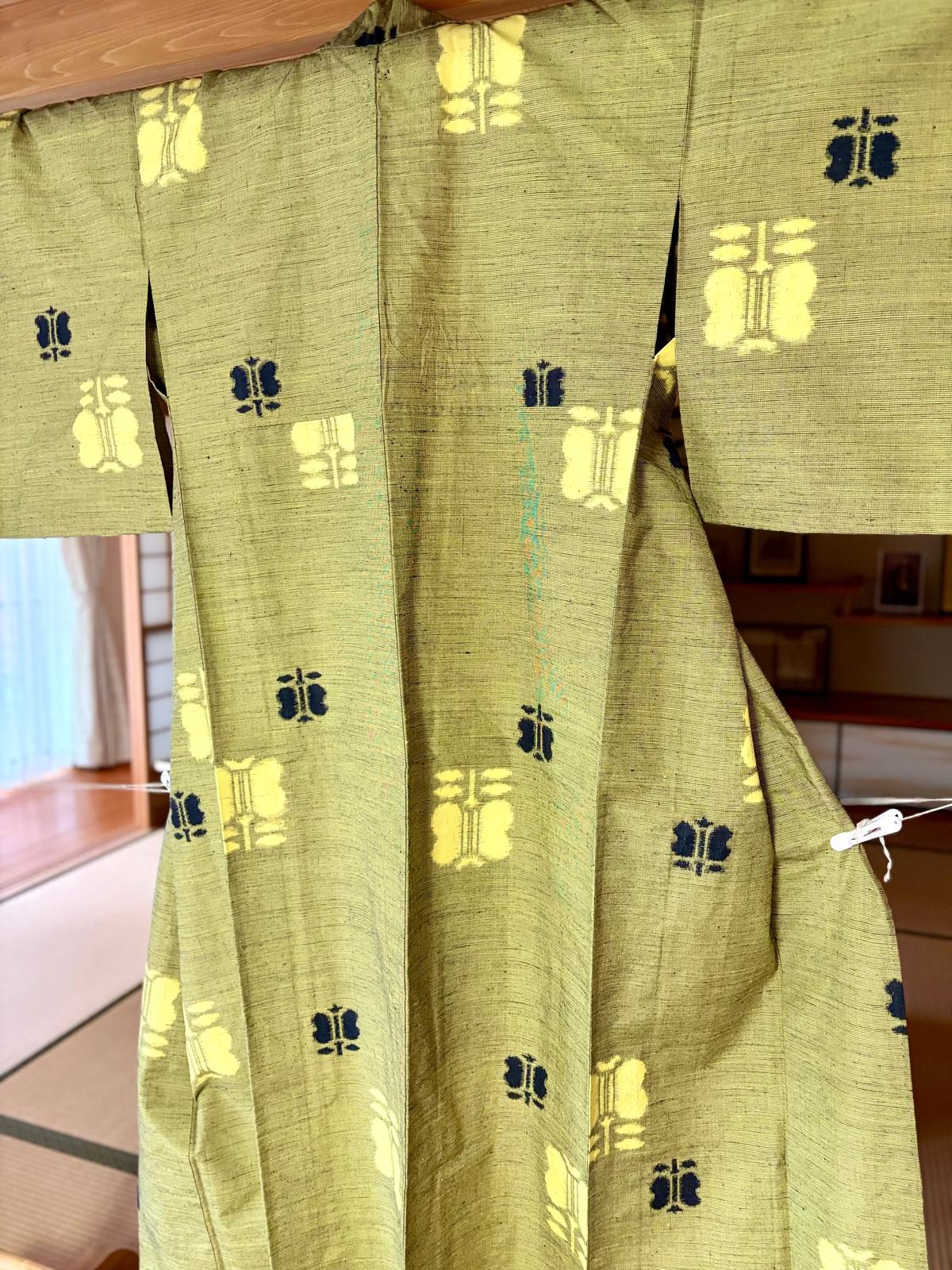 オリーブ色の着物に青と黄の模様が繰り返し配置されている