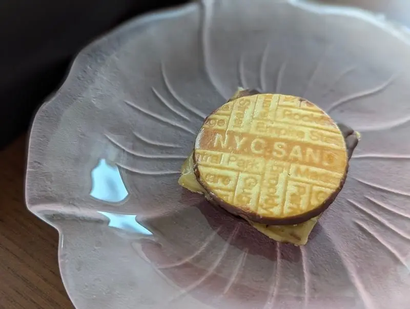 「NYC SAND」という文字が刻まれたサンドイッチが、花びら型のプレートにのっている