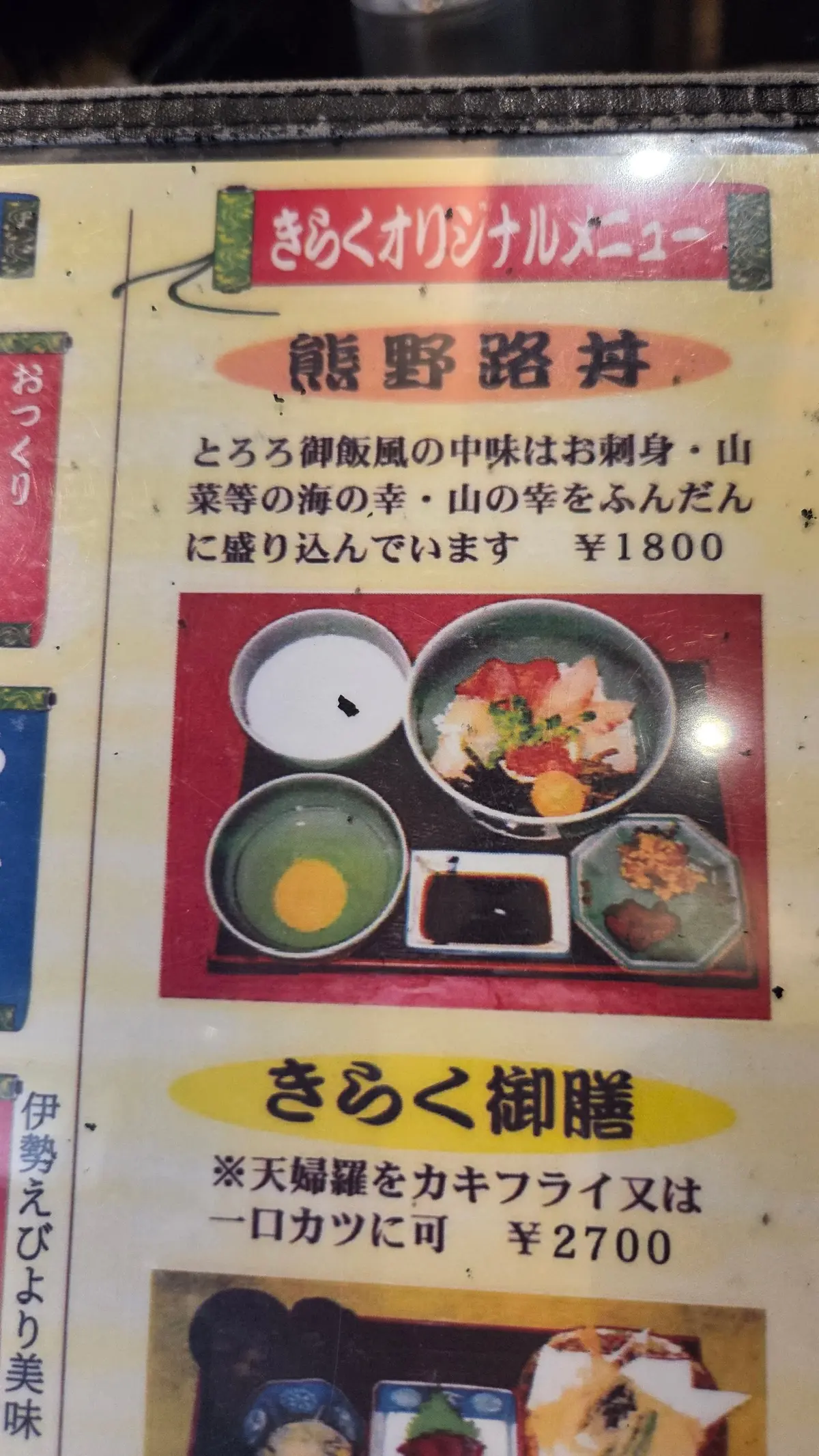 黄色地に黒文字のメニュー。上部は「きのくオリジナルメニュー」、中央は「熊野路丼」のタイトルと料理写真、説明文。「とろろ御飯風の中味はお刺身・山菜等の海の幸・山の幸をふんだんに盛り込んでいます」と記載。料金は1800円。