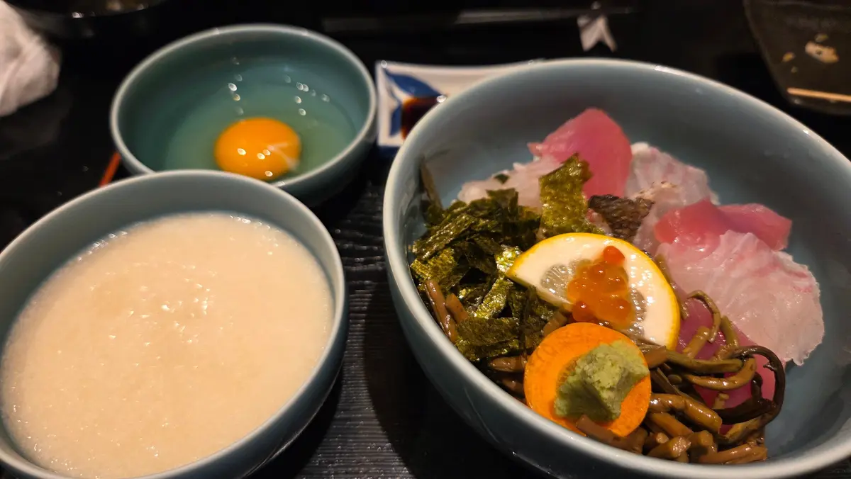青い小鉢3つが並んだ料理。左上には卵、左下には白濁した汁物、右には刺身と海苔、柑橘類が入ったもの。