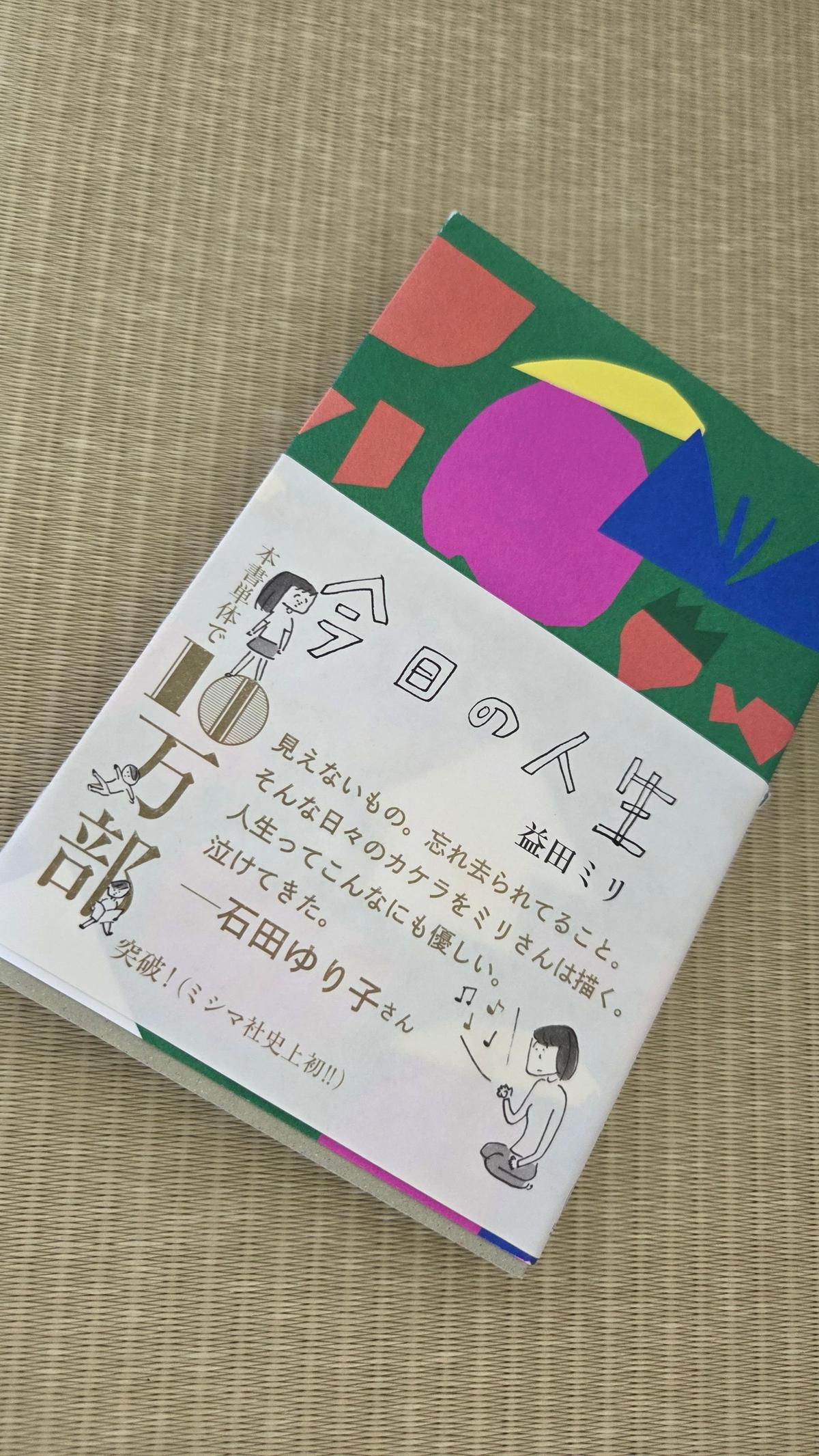 カラフルなイラストが施された本の表紙。「今日の人生」と白文字で大きく書かれ、その下に「五部 裕久」「益田ミリ」などの名前が記載されている。下部には人物のイラストと短い紹介文がある。