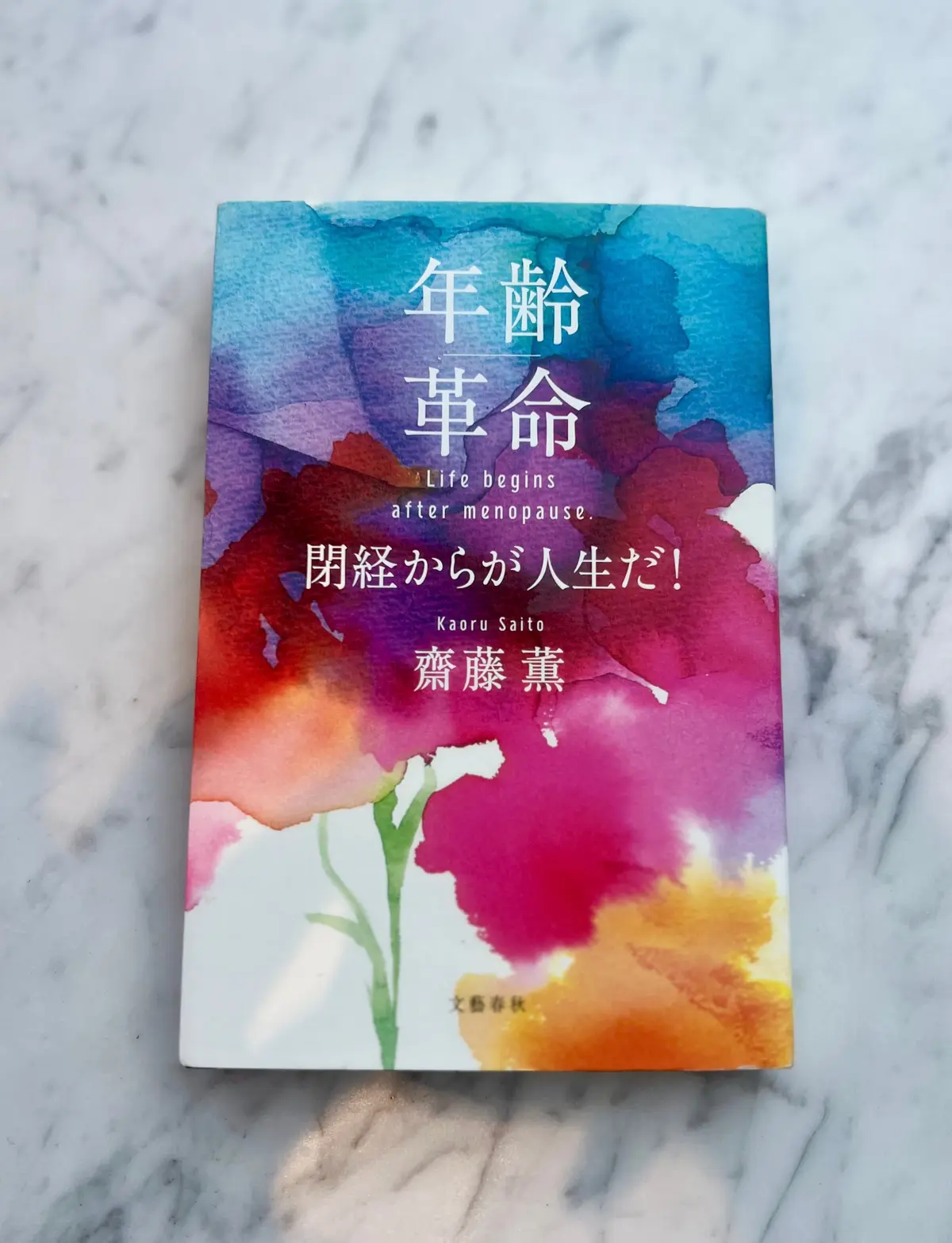 年齢若返りの本表紙、青紫から赤へのグラデーションと花の絵、著者名とサブタイトルが記載