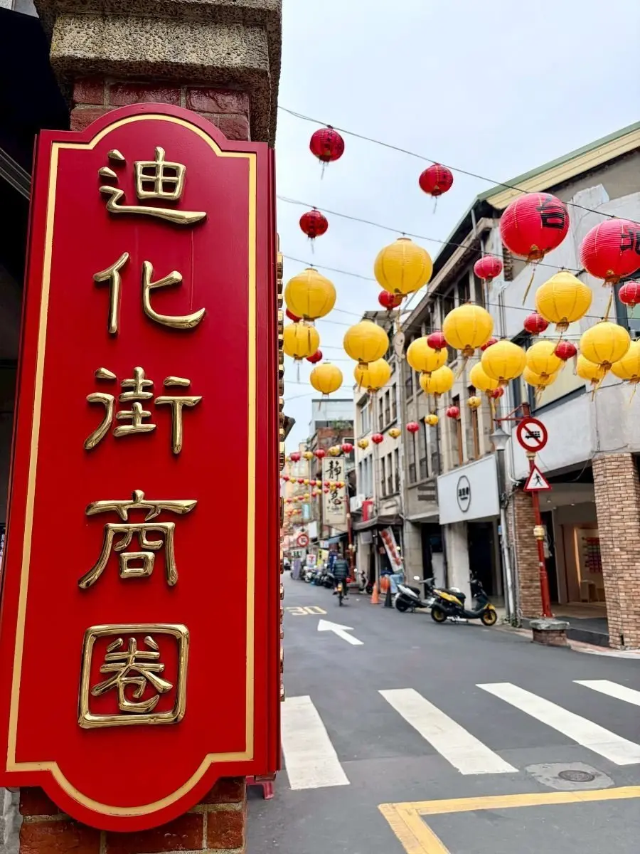 赤い看板に金文字で「迪化街商圏」の文字があり、通りには赤と黄色の提灯が多数吊るされ、商店街の雰囲気がある。