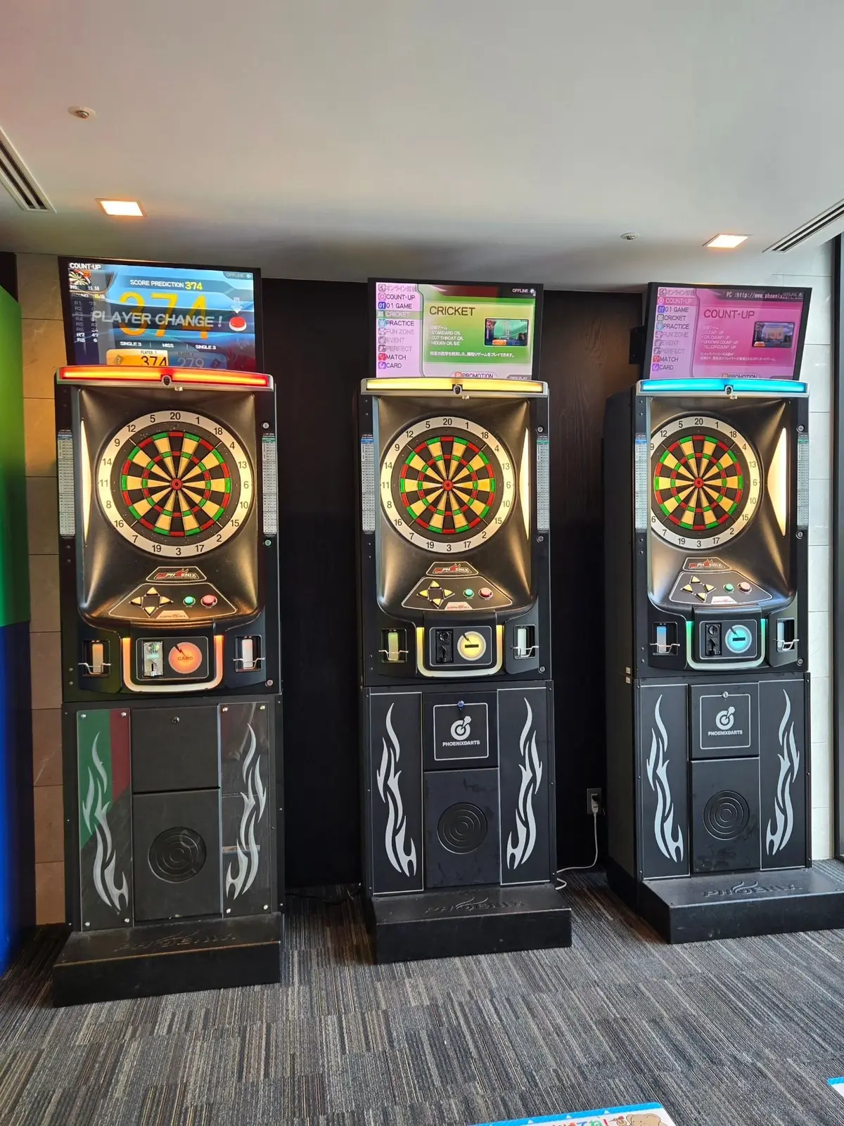 3台のダーツマシンが並んで設置されている様子。黒と白のフレームに、中央にカラフルなダーツボードが配置。上部には液晶モニターが取り付けられている。右下には「PRINCRAFT」のロゴマークがある。