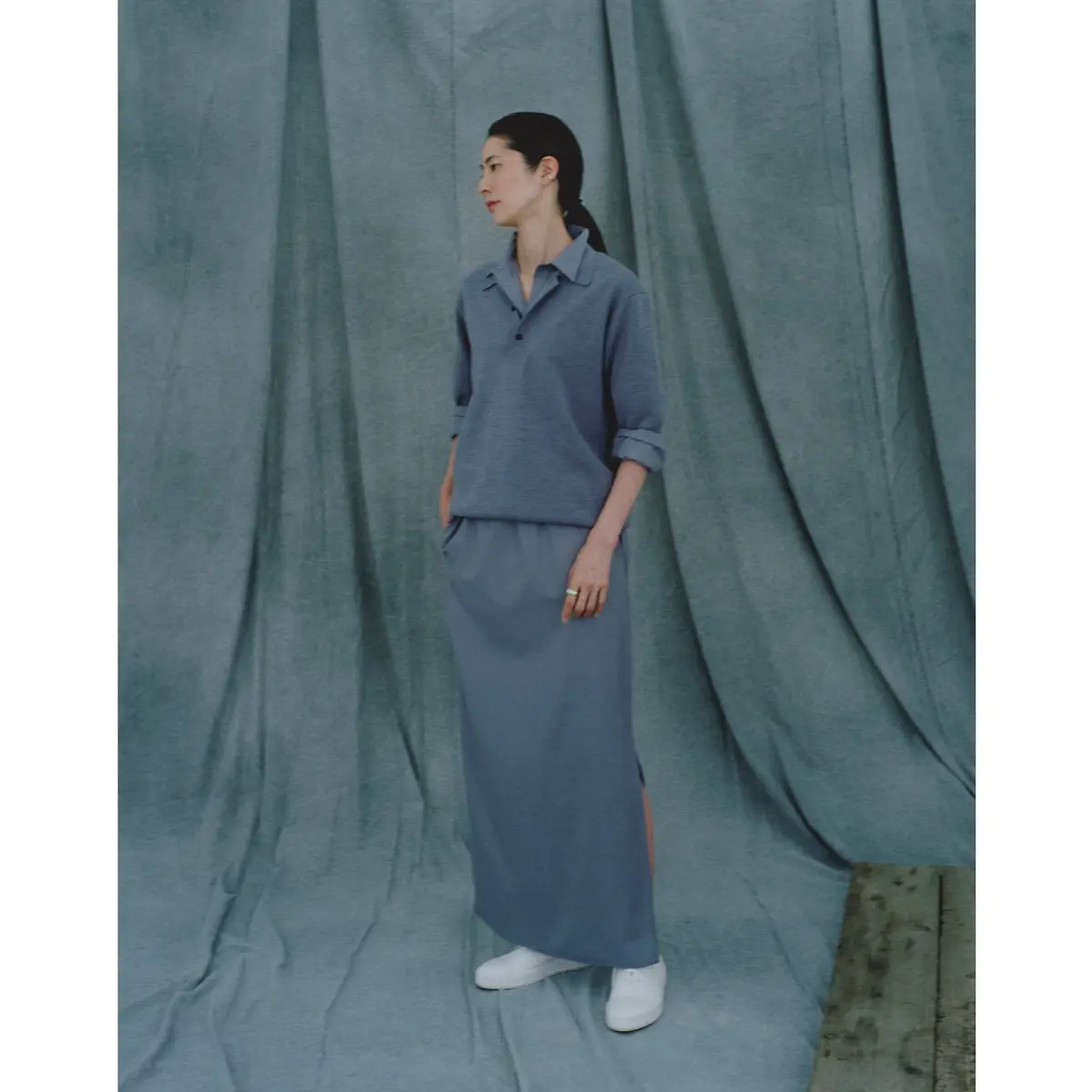 グレーのシャツの上に同色のポロニットを重ね、ロングスカート合わせたワントーンコーディネート　モデル・山村紘未　