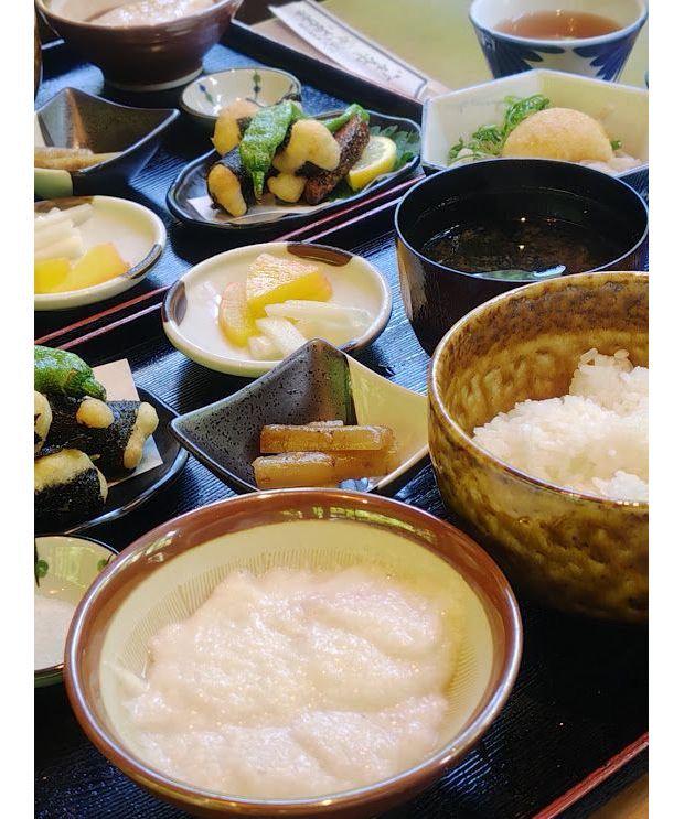 木製のトレイに盛り付けられた、日本の伝統的な定食。ご飯、味噌汁、煮物、お漬物、茶碗蒸しなど、様々な料理が彩り豊かに並んでいる。