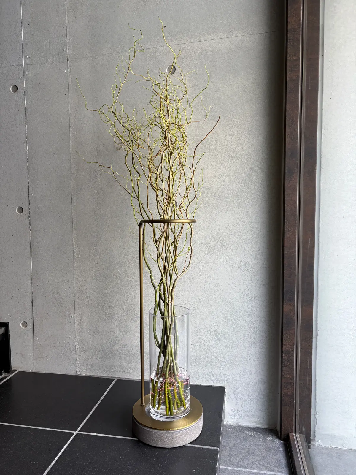 金色の台座とガラス花瓶に生けられた細い枝の装飾花