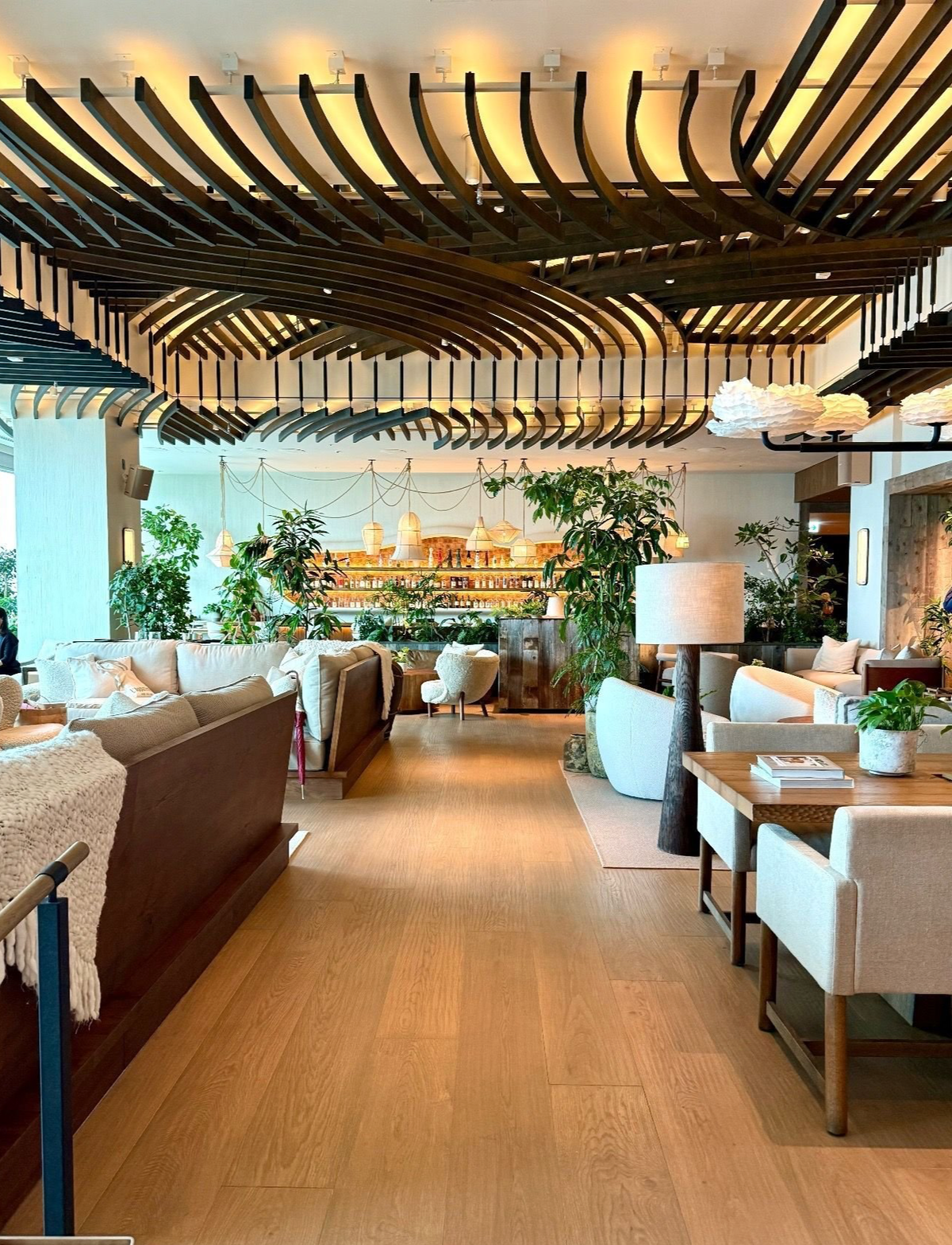 １Hotel Tokyo ３８階　カフェ「Neighbors Café」、木製の天井と自然光が差し込むモダンなラウンジ、ソファやテーブル、緑の植物が配置