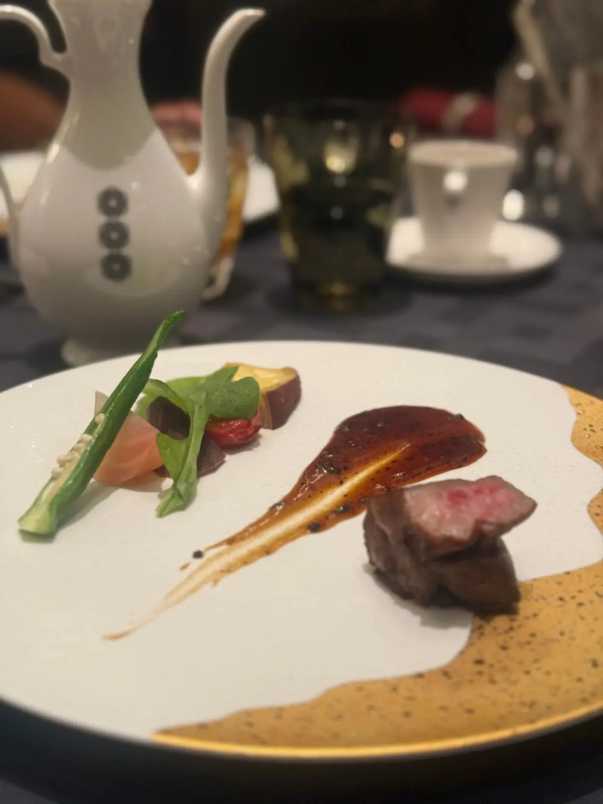 白いプレートに、焼きビーフ、野菜、ソースが芸術的に配置された料理。